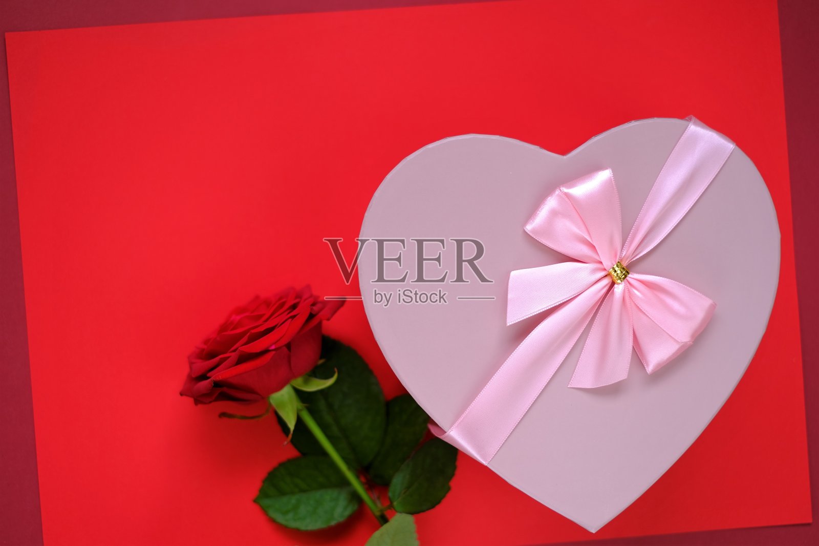 情人节。粉红色的心形盒子与蝴蝶结和红色玫瑰花在明亮的红色背景。空白明信片。爱与激情的概念。情人节礼物。本空间照片摄影图片
