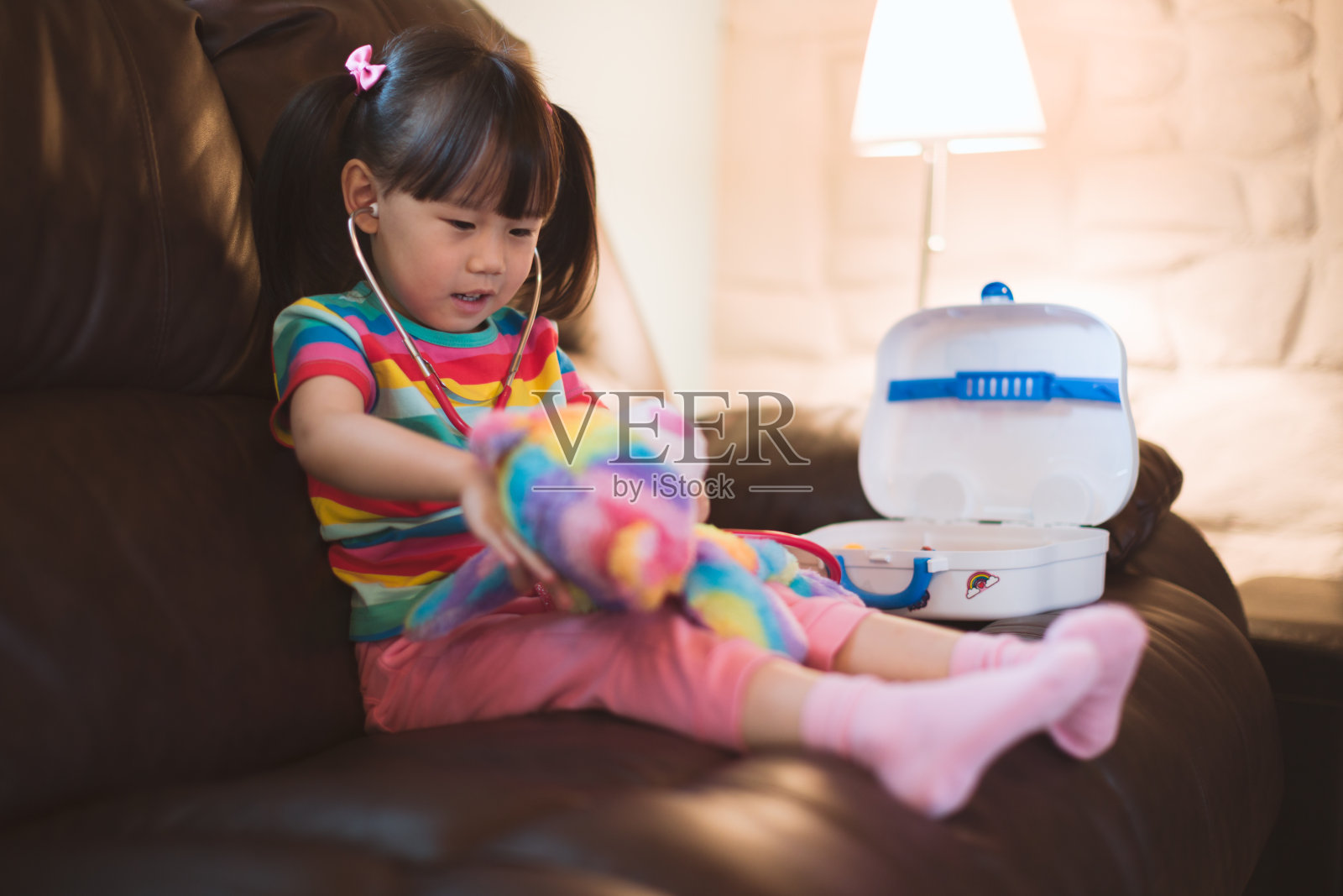 小女孩在客厅里扮演照顾她的熊病人的医生照片摄影图片