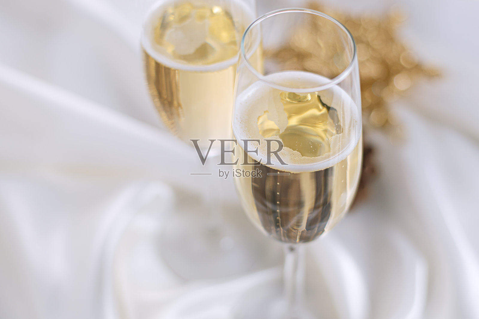 用香槟庆祝圣诞节和新年。两个用白色布料装饰的香槟杯。照片摄影图片