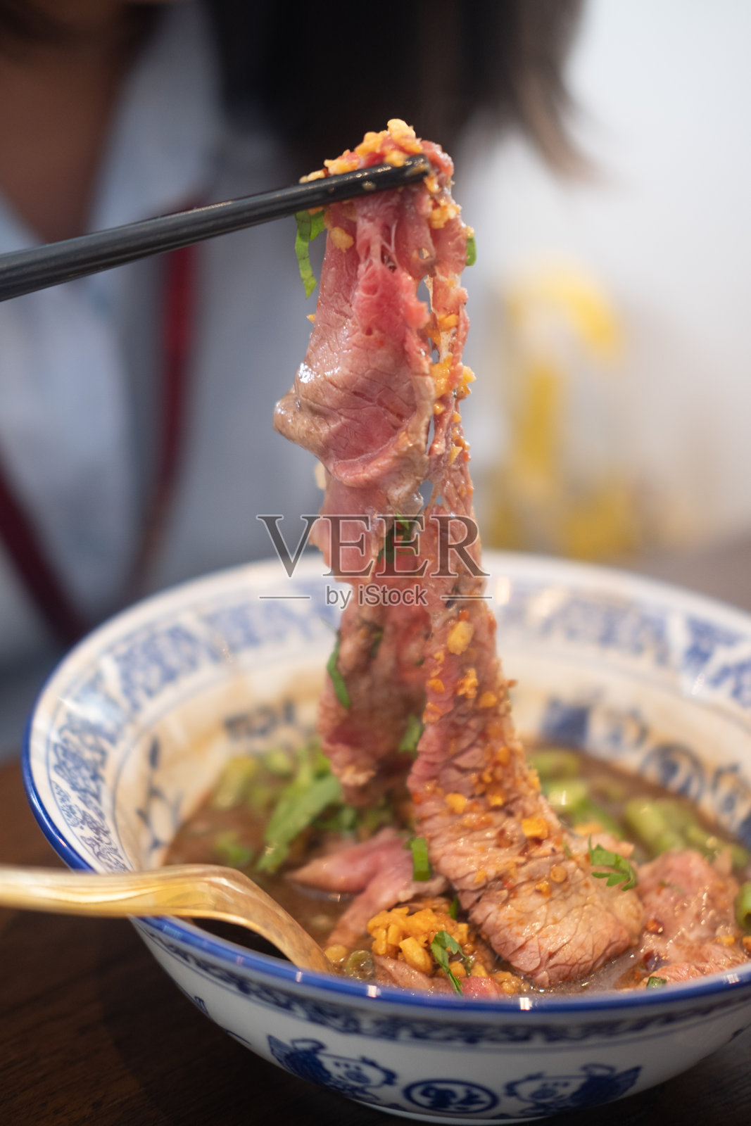 用筷子从泰国面条碗里夹起一片上等的中等生和牛肉。有选择性的重点照片摄影图片