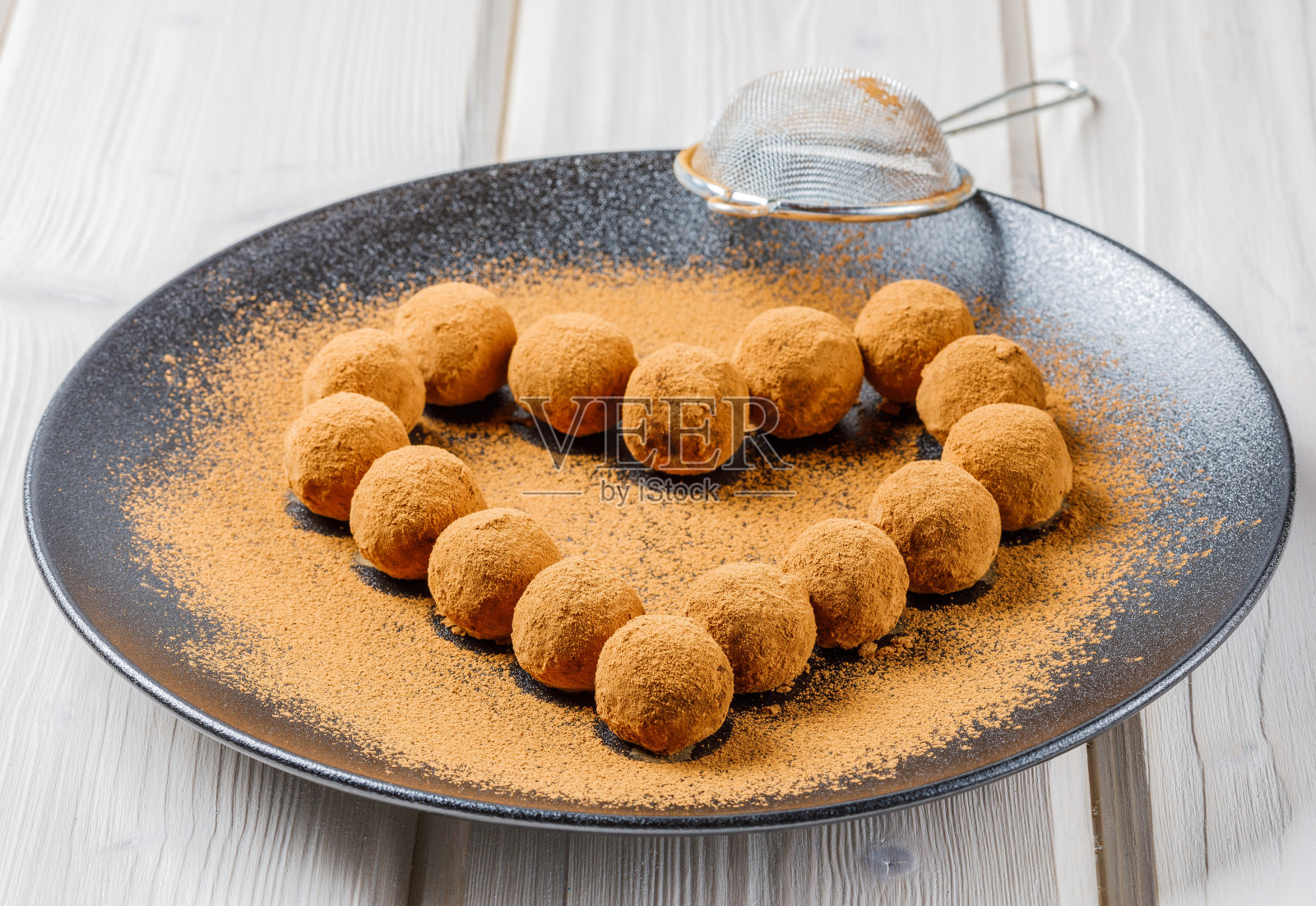 用干枣、核桃、葡萄干做成的巧克力松露或能量蛋白球，上面覆盖可可粉照片摄影图片