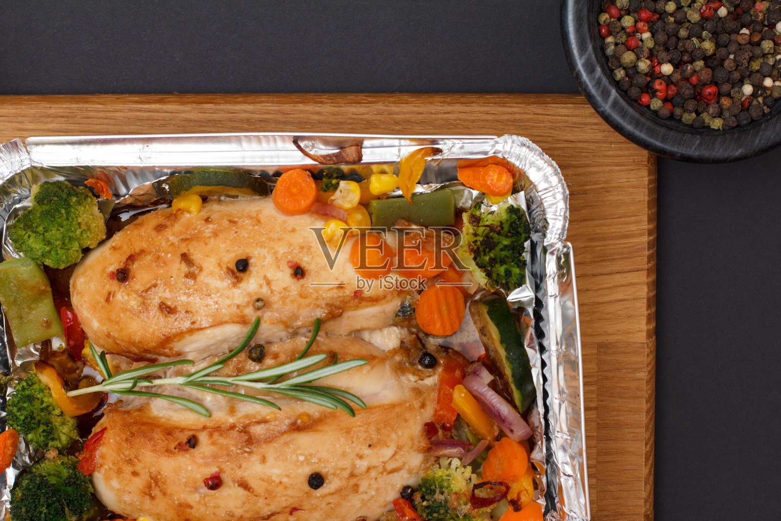 金属容器里的烤鸡胸肉或鱼片配蔬菜。照片摄影图片