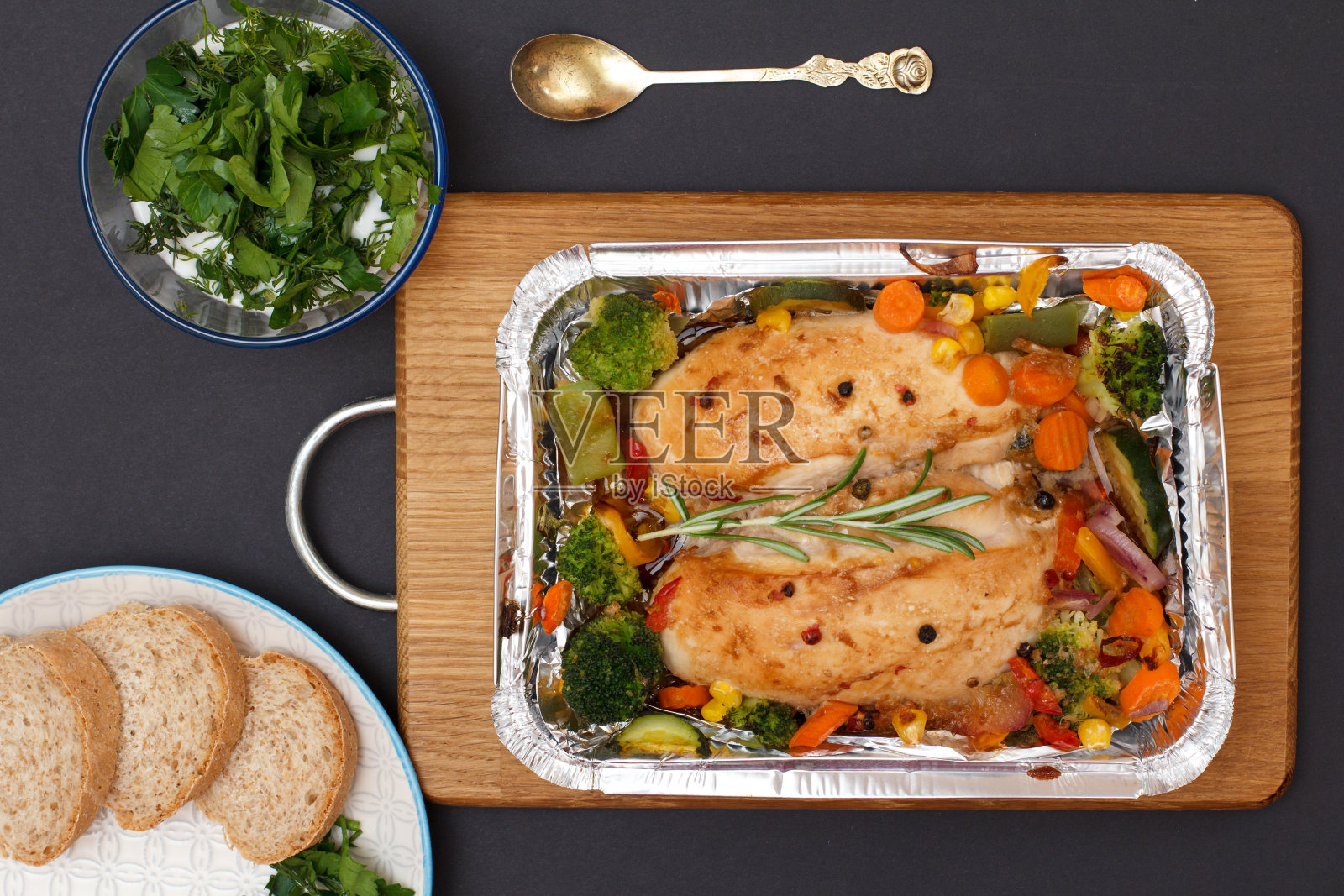 金属容器里的烤鸡胸肉或牛柳，配上蔬菜和面包。照片摄影图片