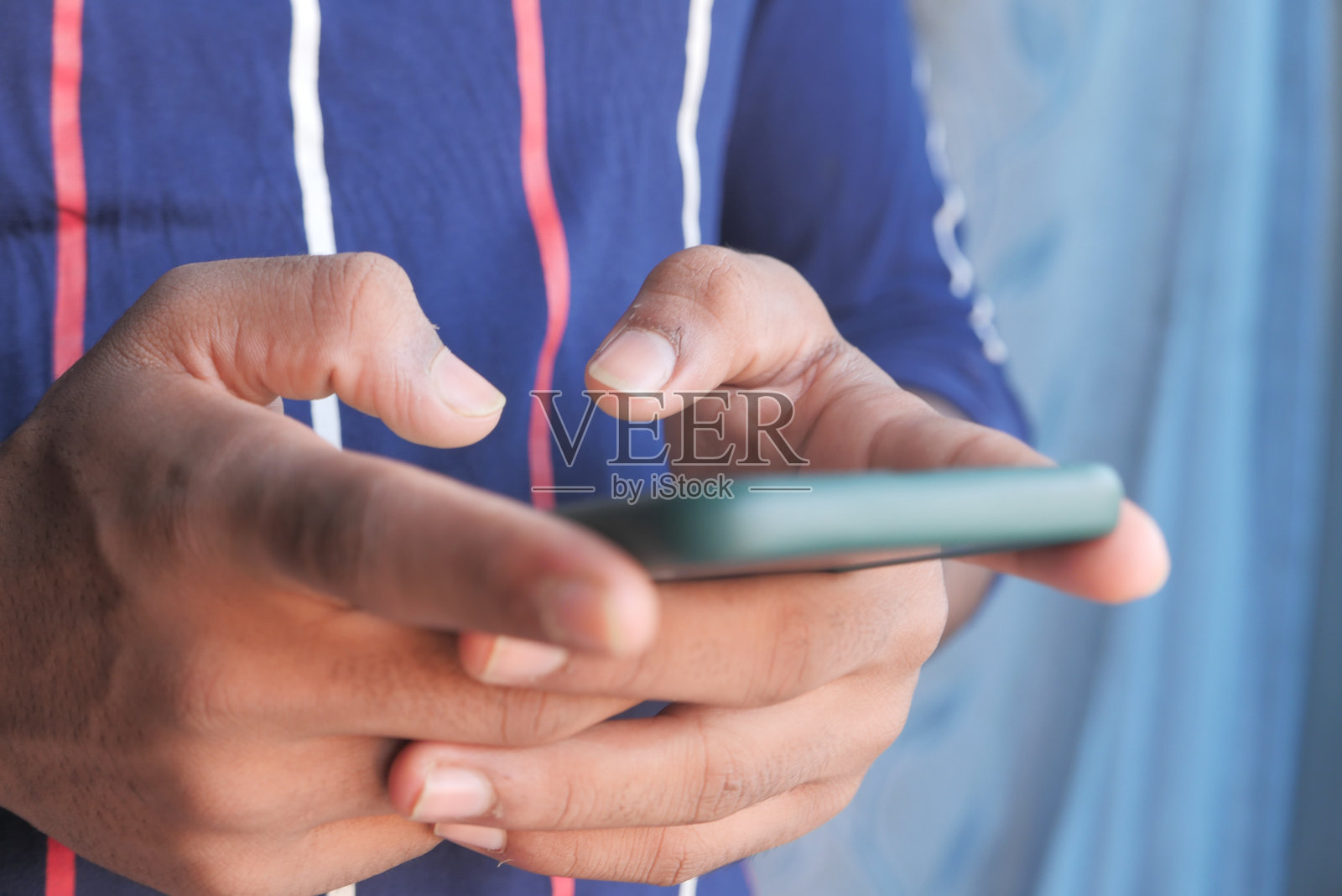 年轻人的手使用智能手机的特写。照片摄影图片