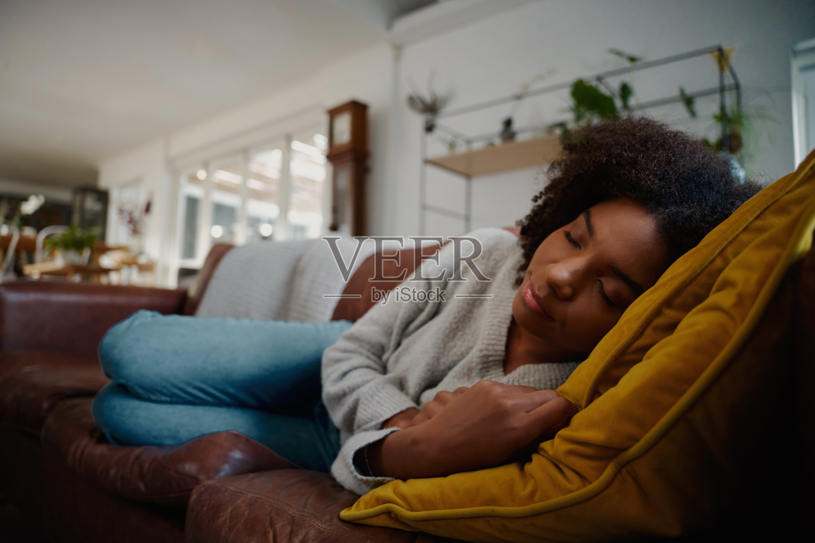 疲惫的年轻女子躺在沙发上打瞌睡，同时做白日梦照片摄影图片