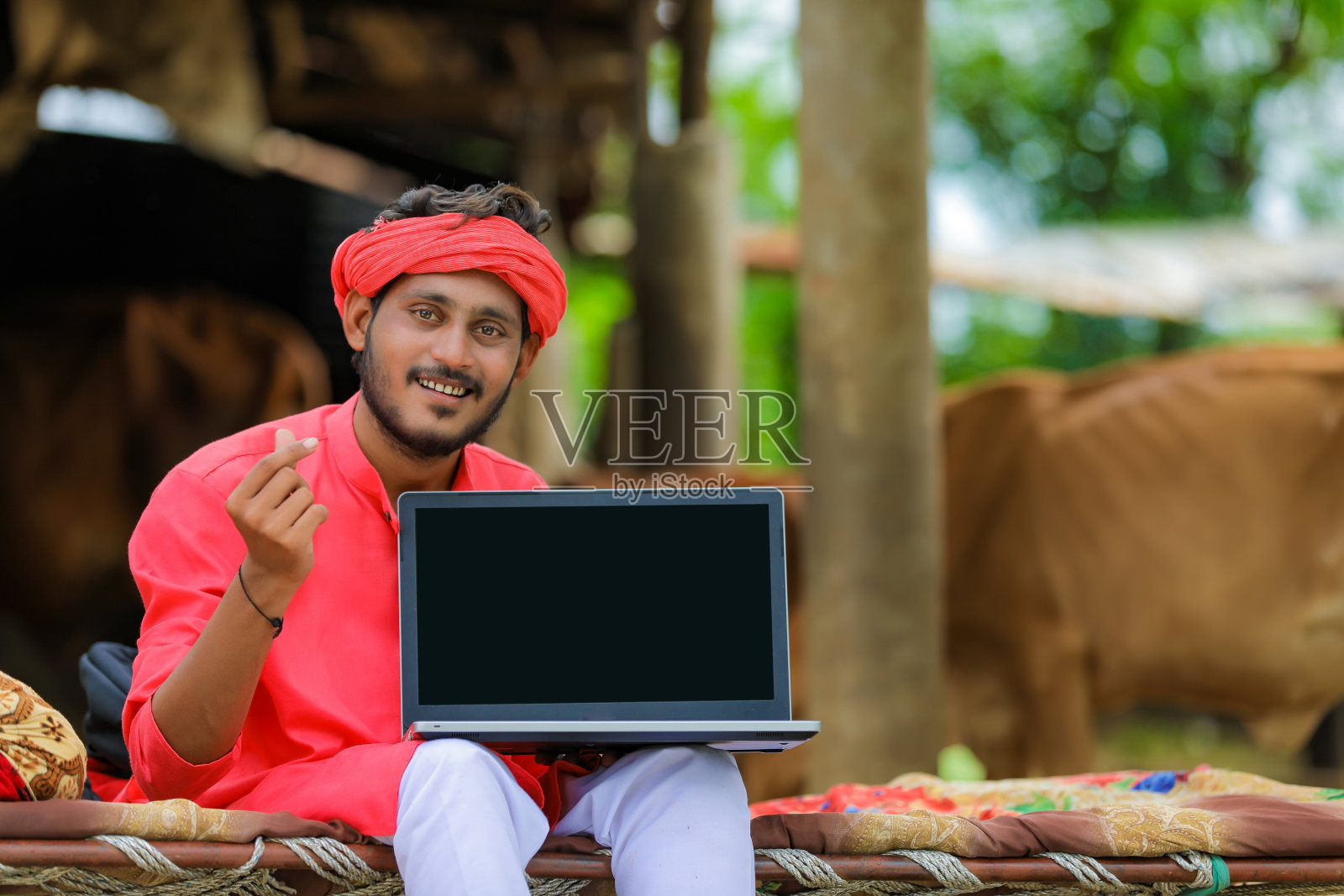 年轻的印度农民在家里展示笔记本电脑的空白屏幕照片摄影图片