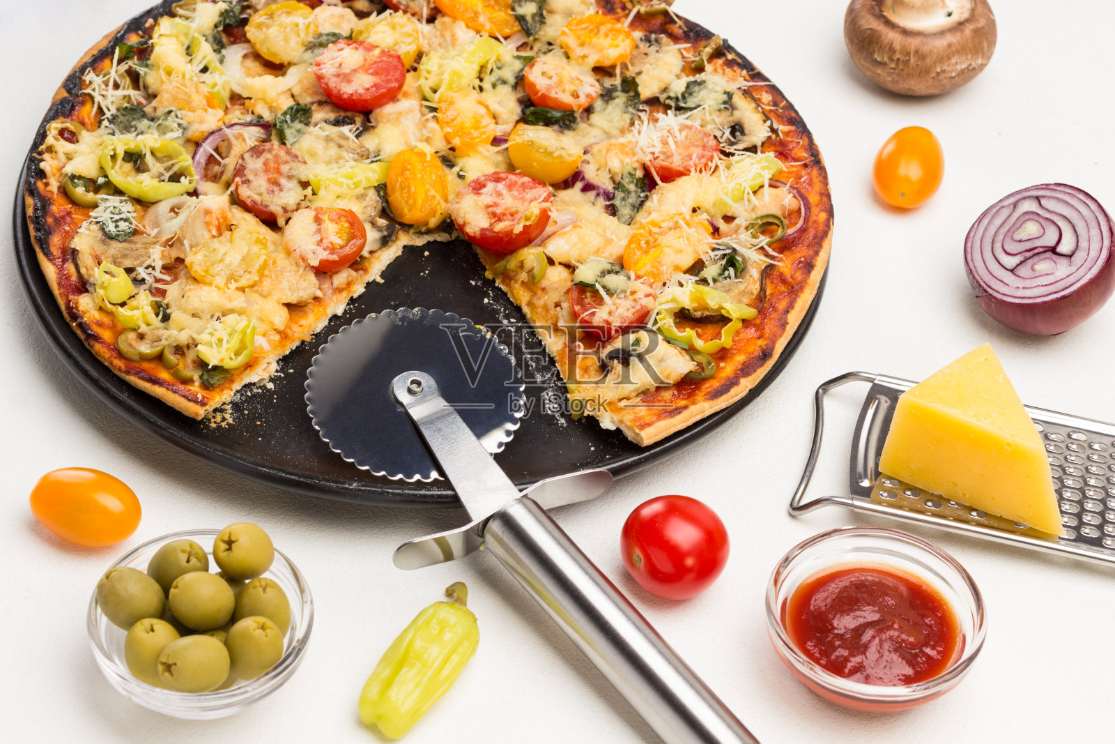 准备好的披萨放在黑色的盘子里。披萨切刀。照片摄影图片