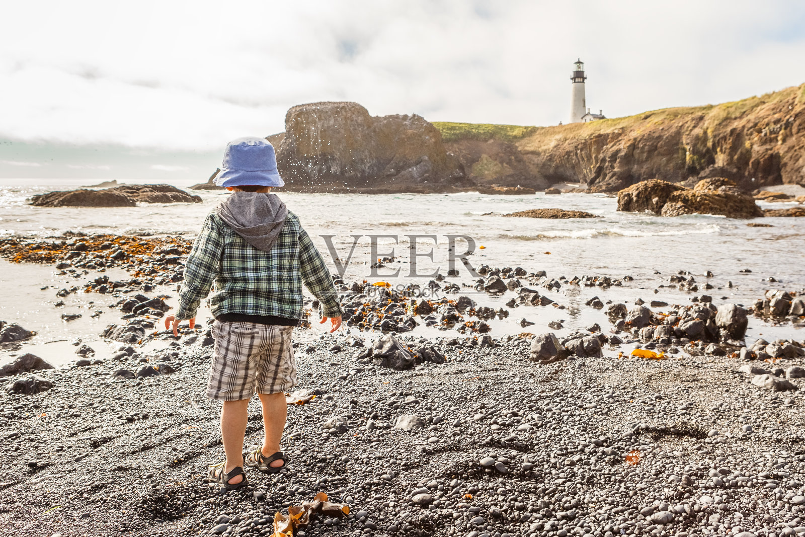 小男孩探索鹅卵石海滩，雅奎纳头照片摄影图片