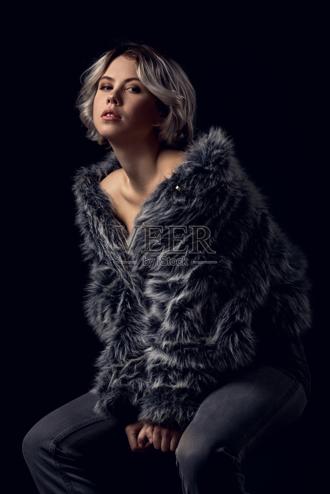 年轻女子奢华风格孤立地坐在灰色墙壁上的椅子上照片摄影图片