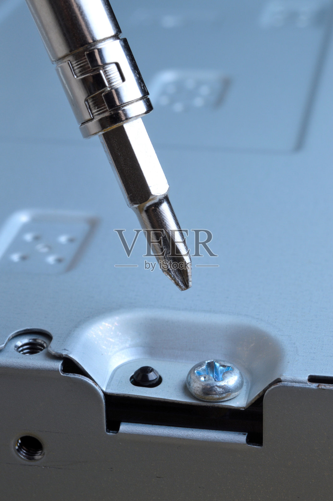 用小螺丝刀拆卸电脑的金属外壳。照片摄影图片