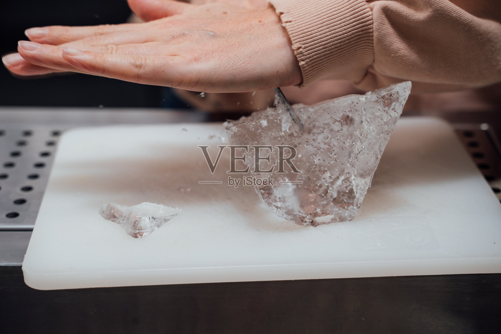 用钢刀手工雕刻鸡尾酒冰块。照片摄影图片