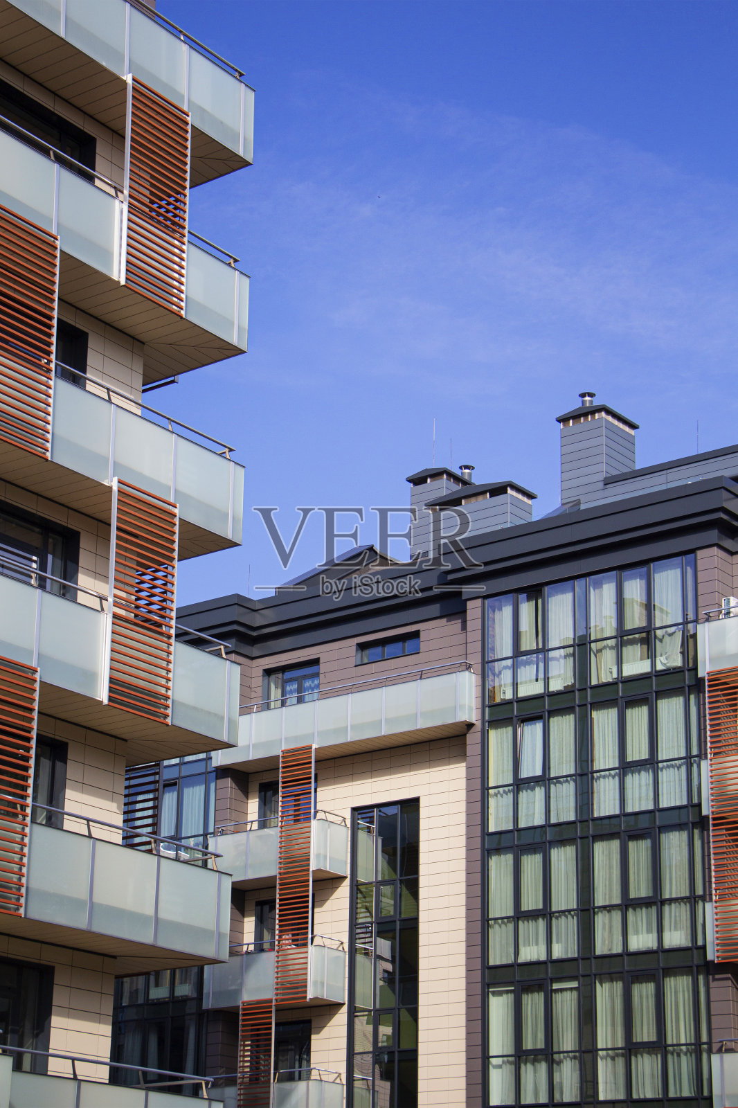 在晴朗的日子里，现代化的公寓大楼映衬着蓝天。照片摄影图片