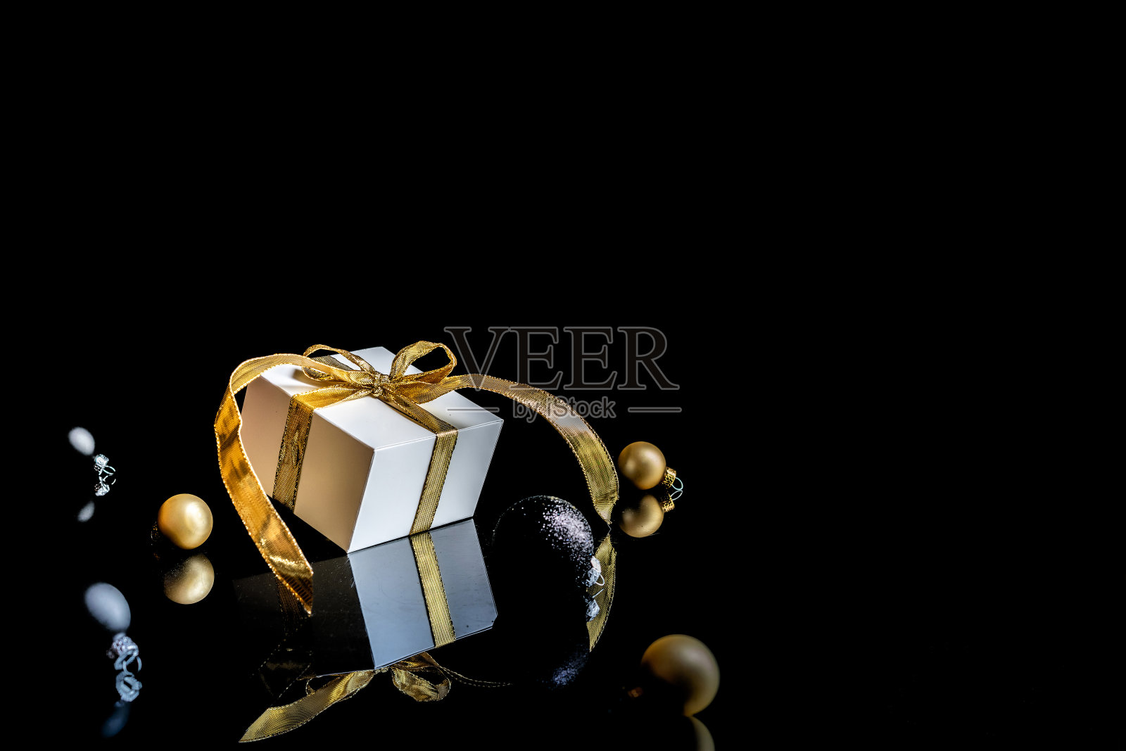 冬季背景黄金。白色礼物与金色的弓，金色的球和新年树在圣诞装饰在黑色的背景贺卡。圣诞背景与文字空间。照片摄影图片