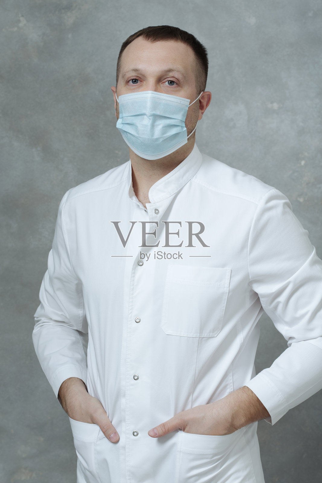 一个非常严肃的医生，穿着白大褂，戴着蓝色的防护面具照片摄影图片