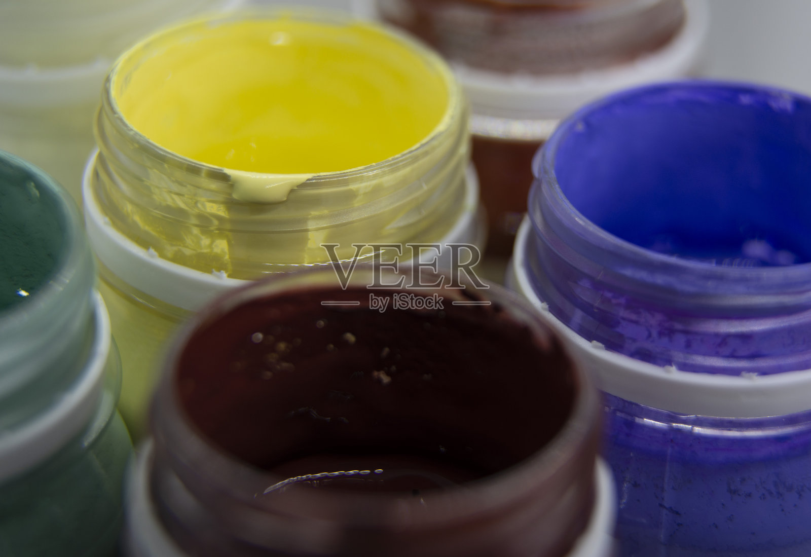 瓶口装着红色、黄色、紫色的丙烯酸颜料。照片摄影图片