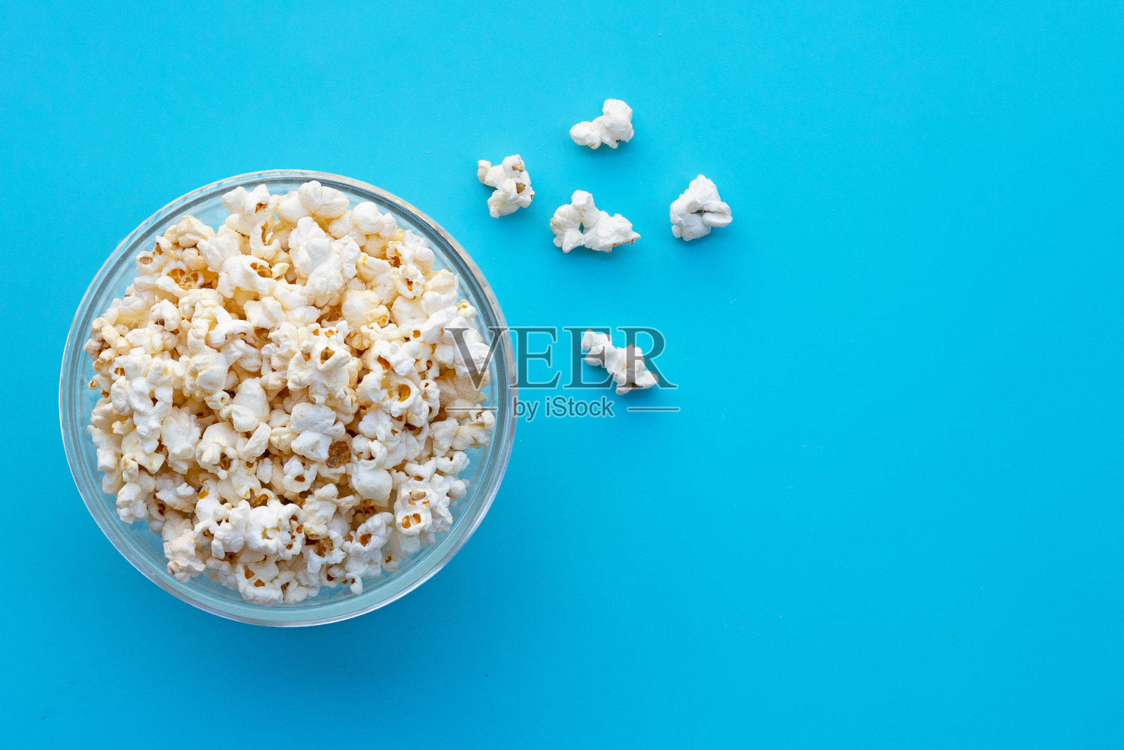 蓝色背景上的爆米花。本空间照片摄影图片