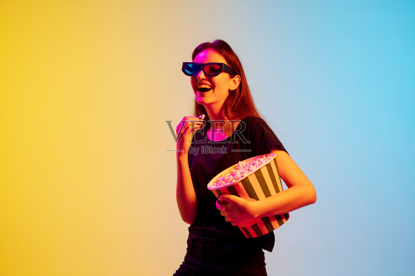 年轻的白人妇女的肖像在渐变蓝黄色的工作室背景霓虹灯照片摄影图片