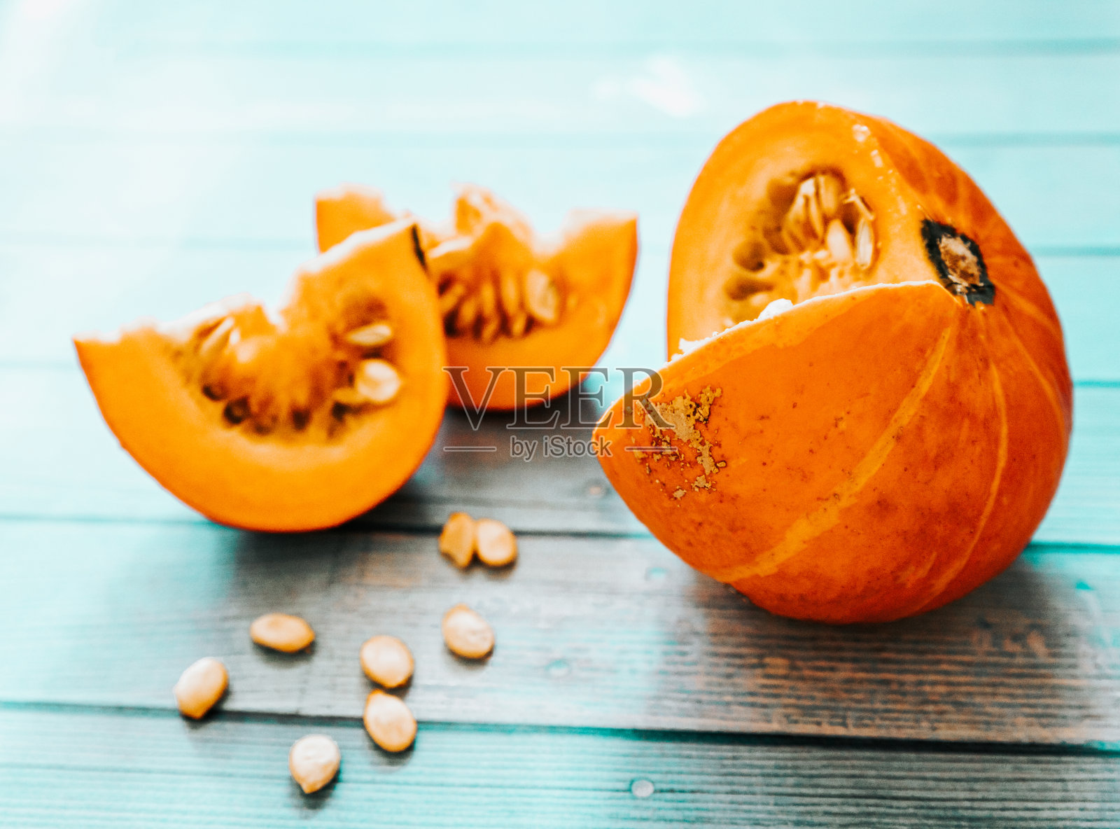 橙色成熟的南瓜和秋天的叶子放在一个木制的蓝色纹理的桌子上。桌上放着白色的南瓜子。有纹理的蓝色桌子上放着成熟的橙色南瓜。秋天的静物画，南瓜和橡子放在轻便的餐桌上照片摄影图片