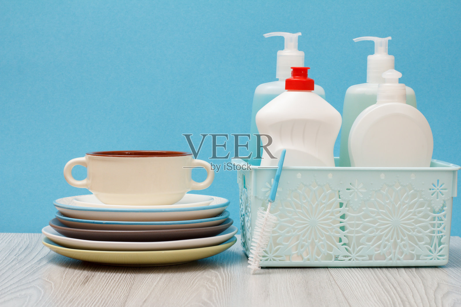 蓝色背景的洗洁精瓶和盘子。照片摄影图片