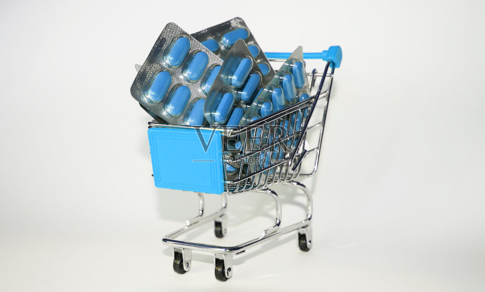 蓝色购物车与蓝色胶囊水泡在白色的背景，医药经营概念，流行病照片摄影图片