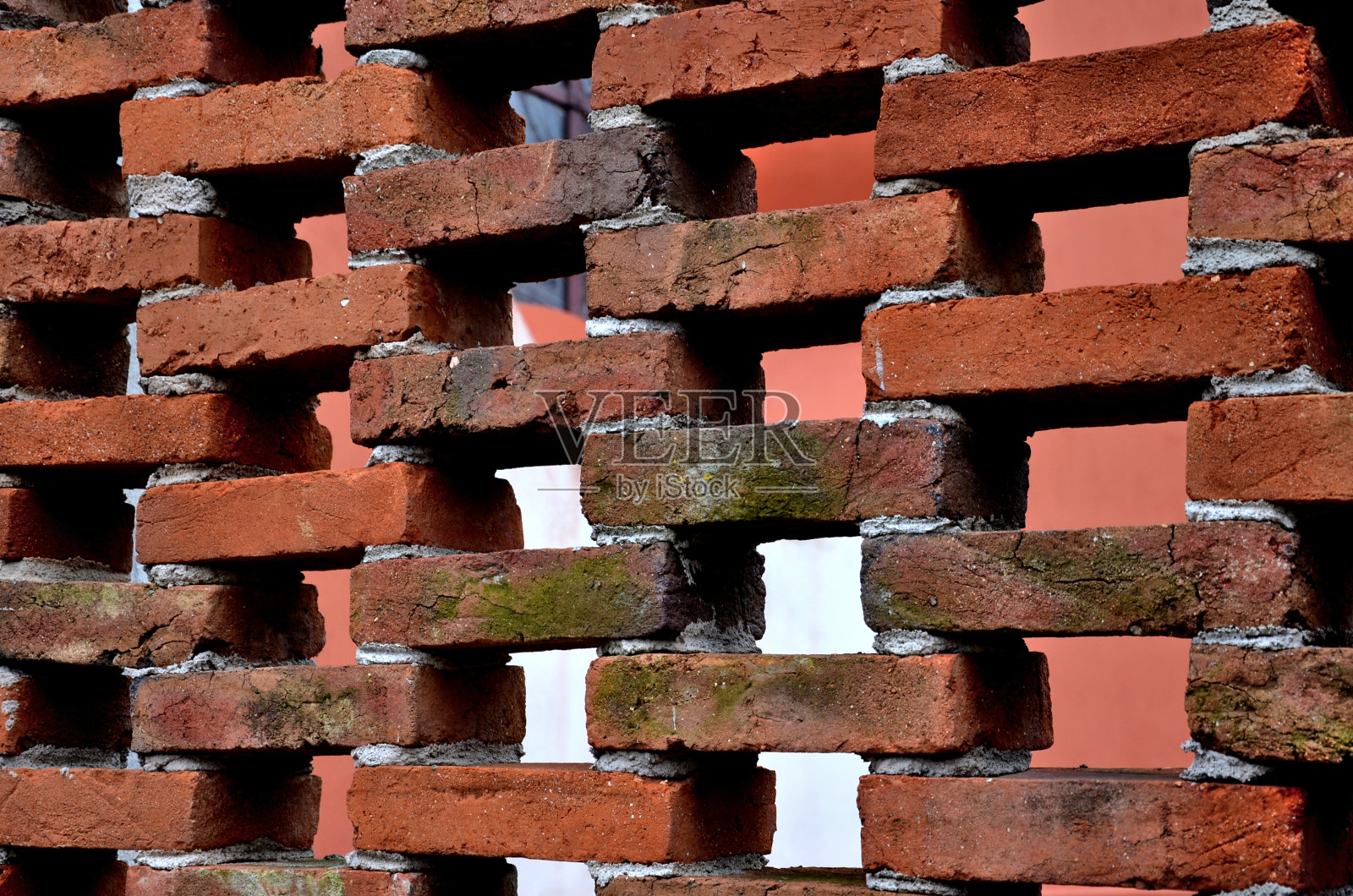 红色的栅栏围绕着花园，用烧过的粘土砖砌成，有很大的缝隙。通过水泥砂浆连接的巨大立方体结构创建了一个轻结构。砖石行业照片摄影图片