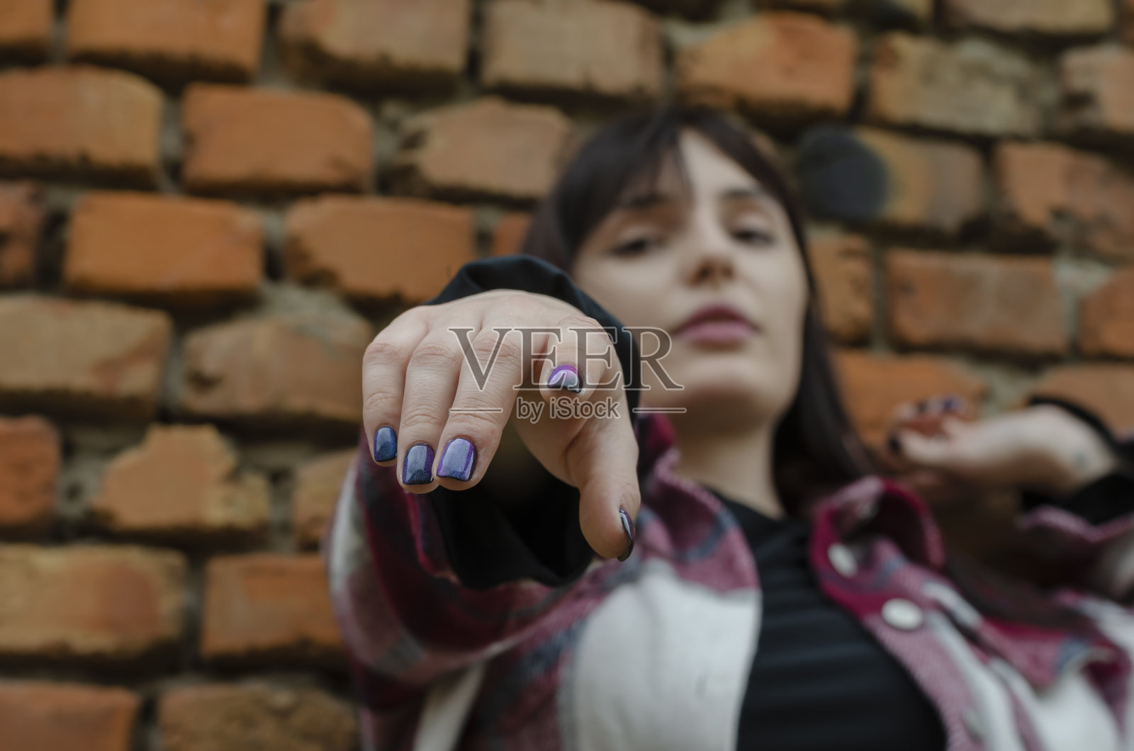 年轻女子伸手拿起相机。照片摄影图片