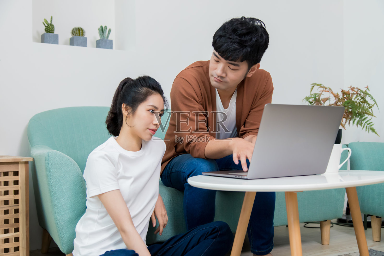 亚洲女人和男人在家里用笔记本电脑工作和思考。照片摄影图片