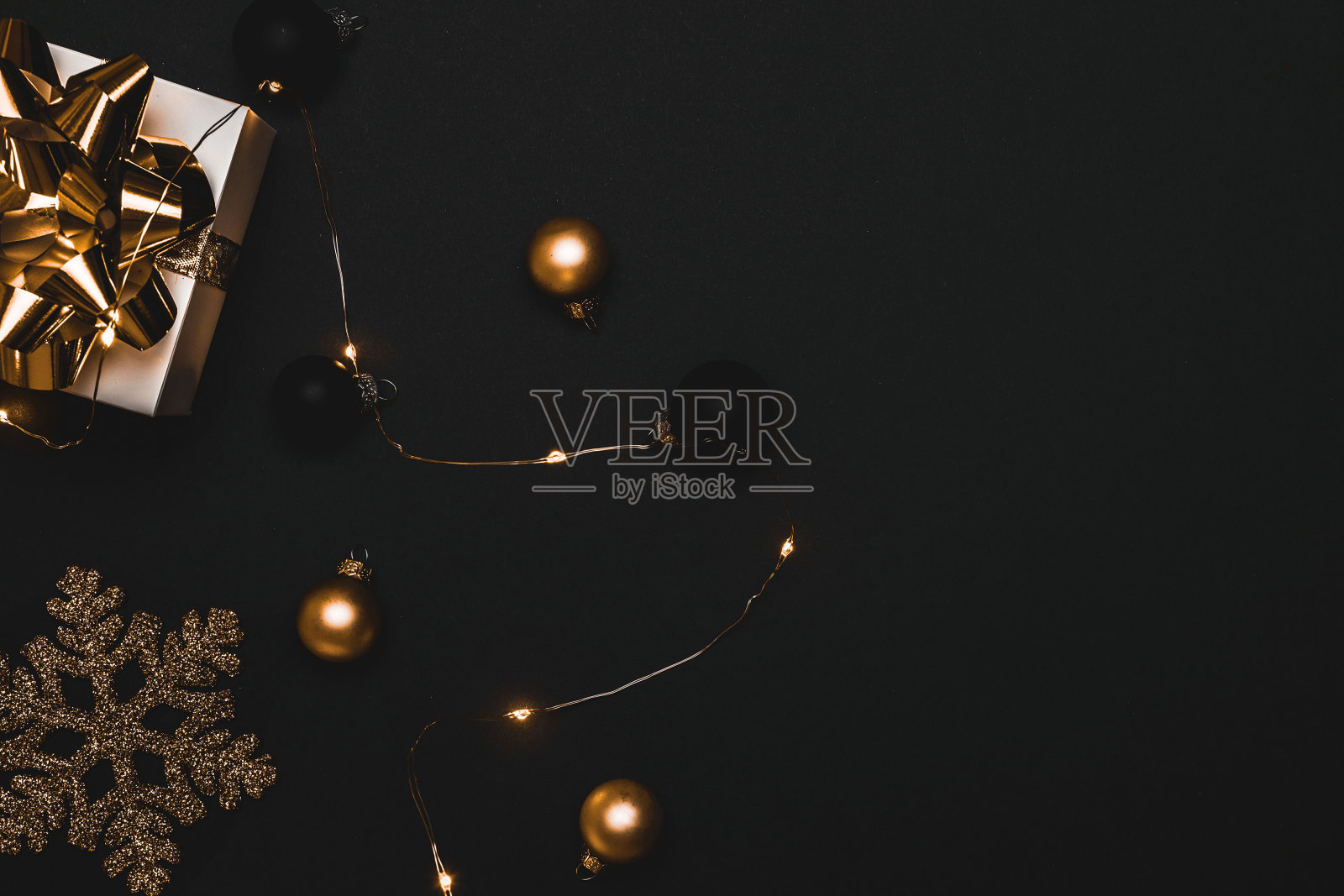 圣诞节销售。白色的礼物与金色的弓，金色的球和闪闪发光的灯花环在圣诞装饰在黑暗的背景贺卡。圣诞节，冬天，新年的概念。照片摄影图片