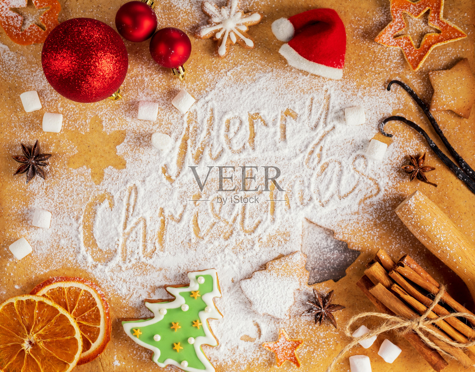 圣诞节烘焙背景。圣诞装饰物，姜饼曲奇，干橙，桂皮棒，八角星形和擀面杖姜饼烤面团的背景。题词圣诞快乐，俯视图。照片摄影图片