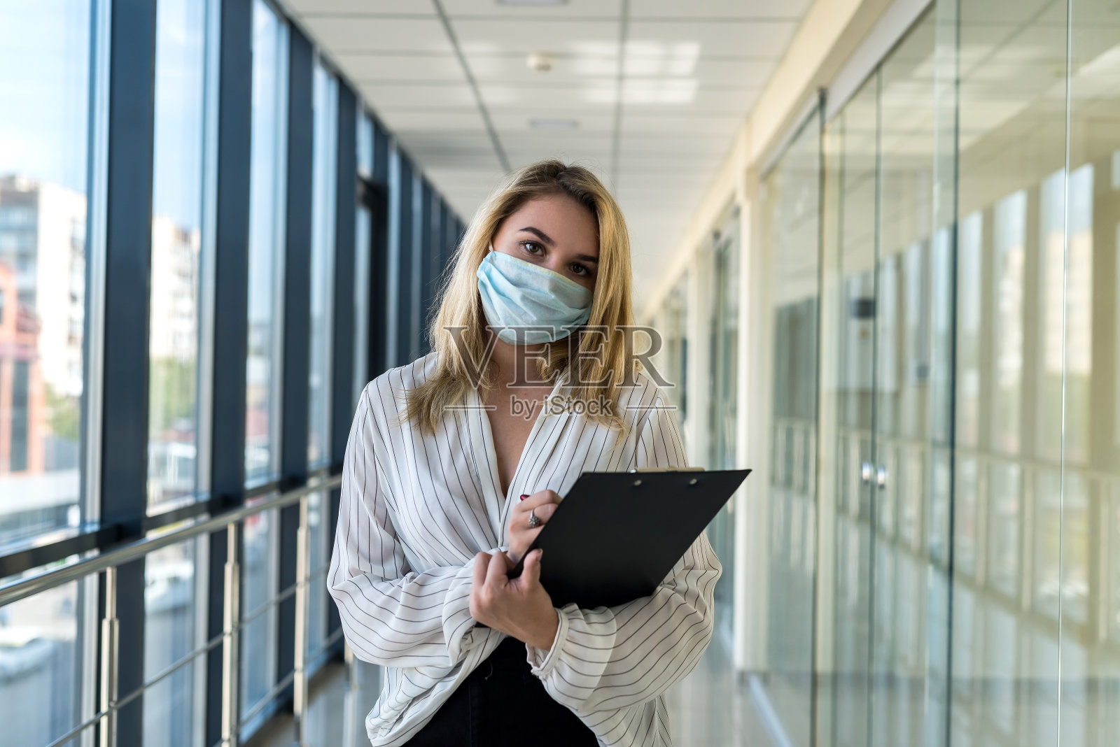 商务女士站在现代商业中心的走廊上在写字板上写字照片摄影图片