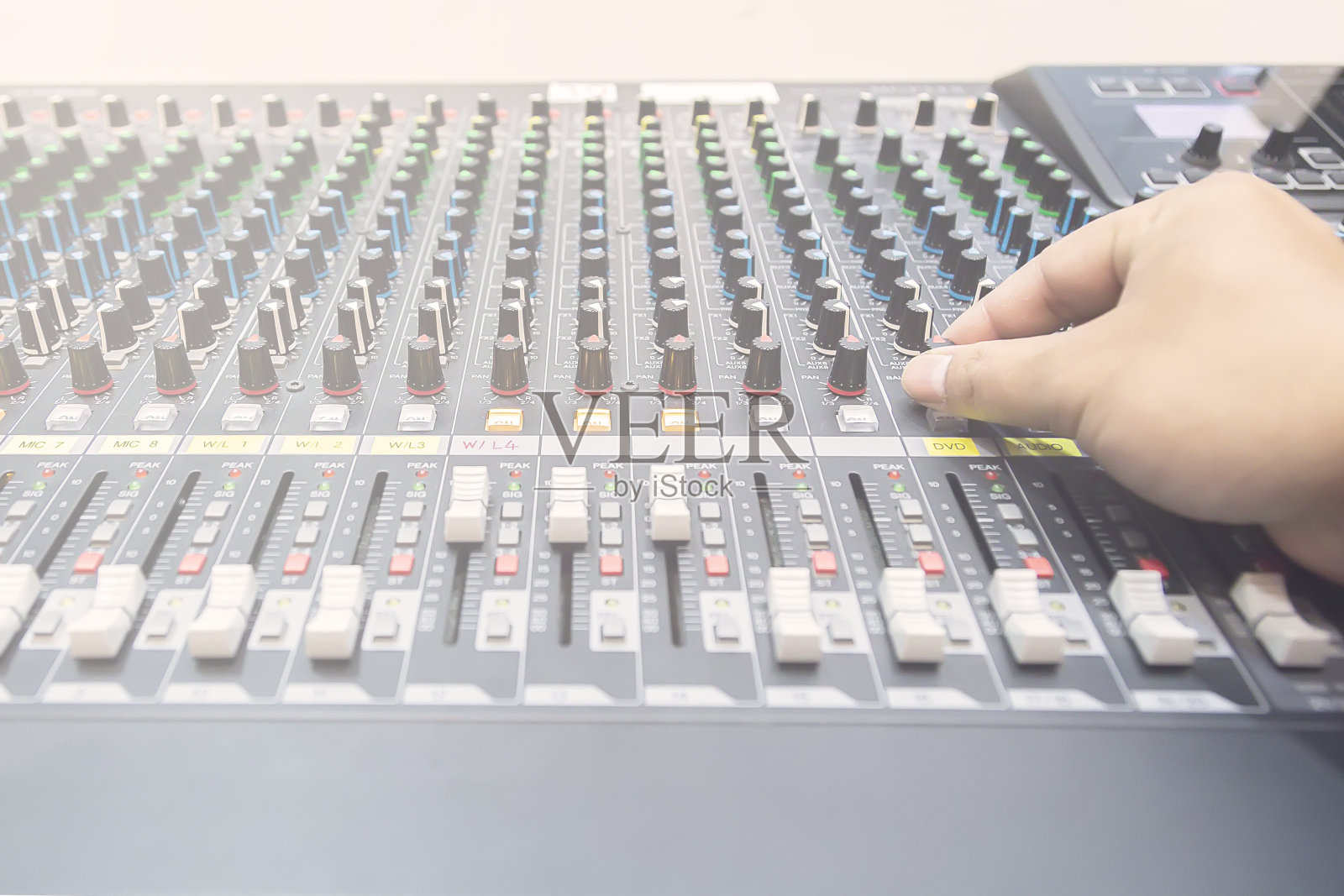 手动调音器正在调音。手按音频混音器上的按钮。照片摄影图片