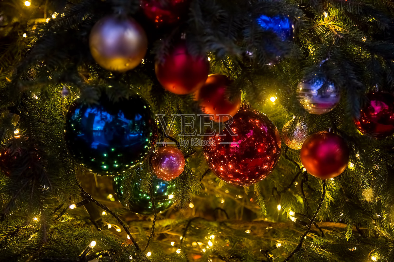 这是一个有装饰球、玩具和闪亮花环的圣诞树树枝的特写。软焦点，背景模糊。照片摄影图片