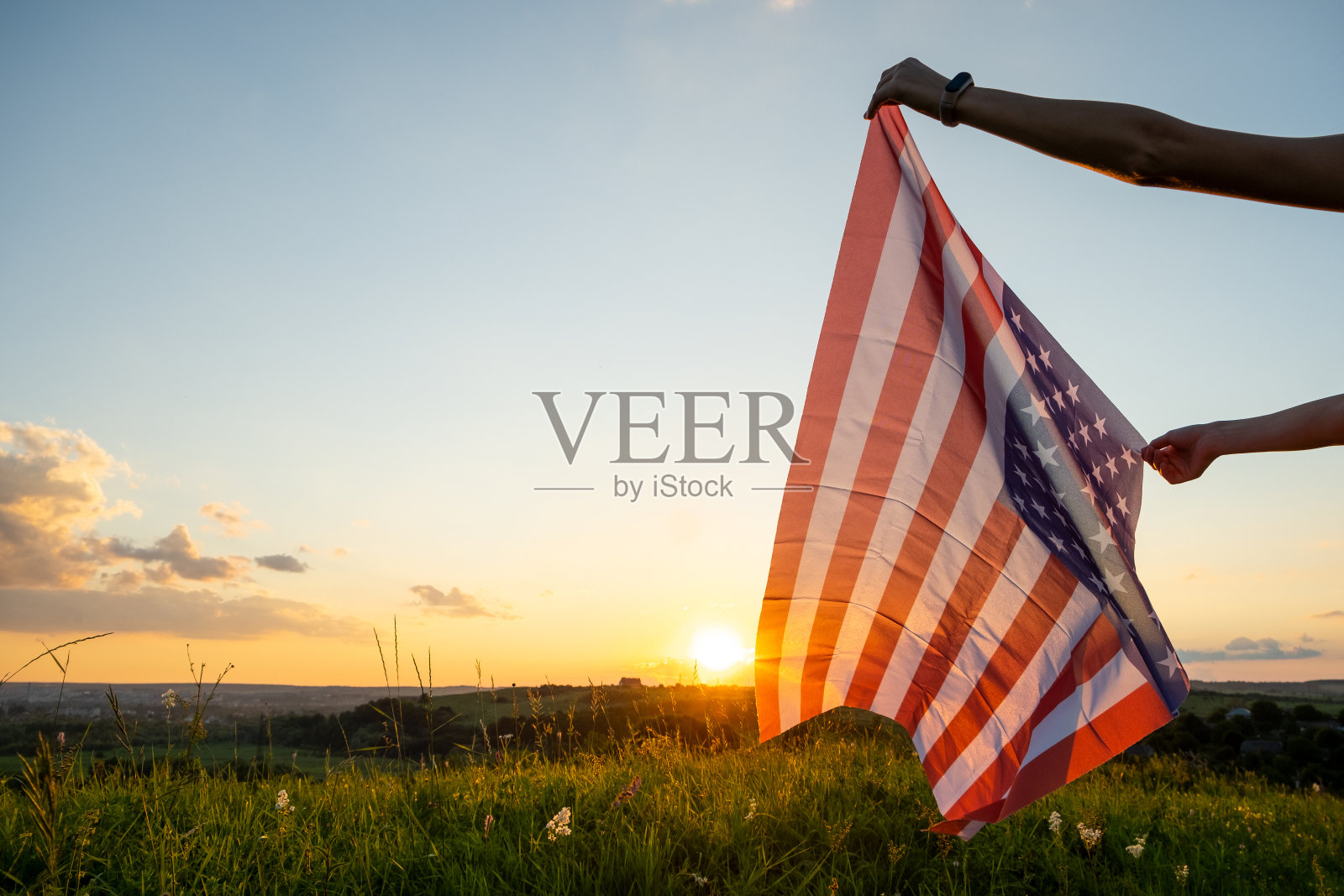 日落时分，人们在田野上挥舞着美国国旗。照片摄影图片