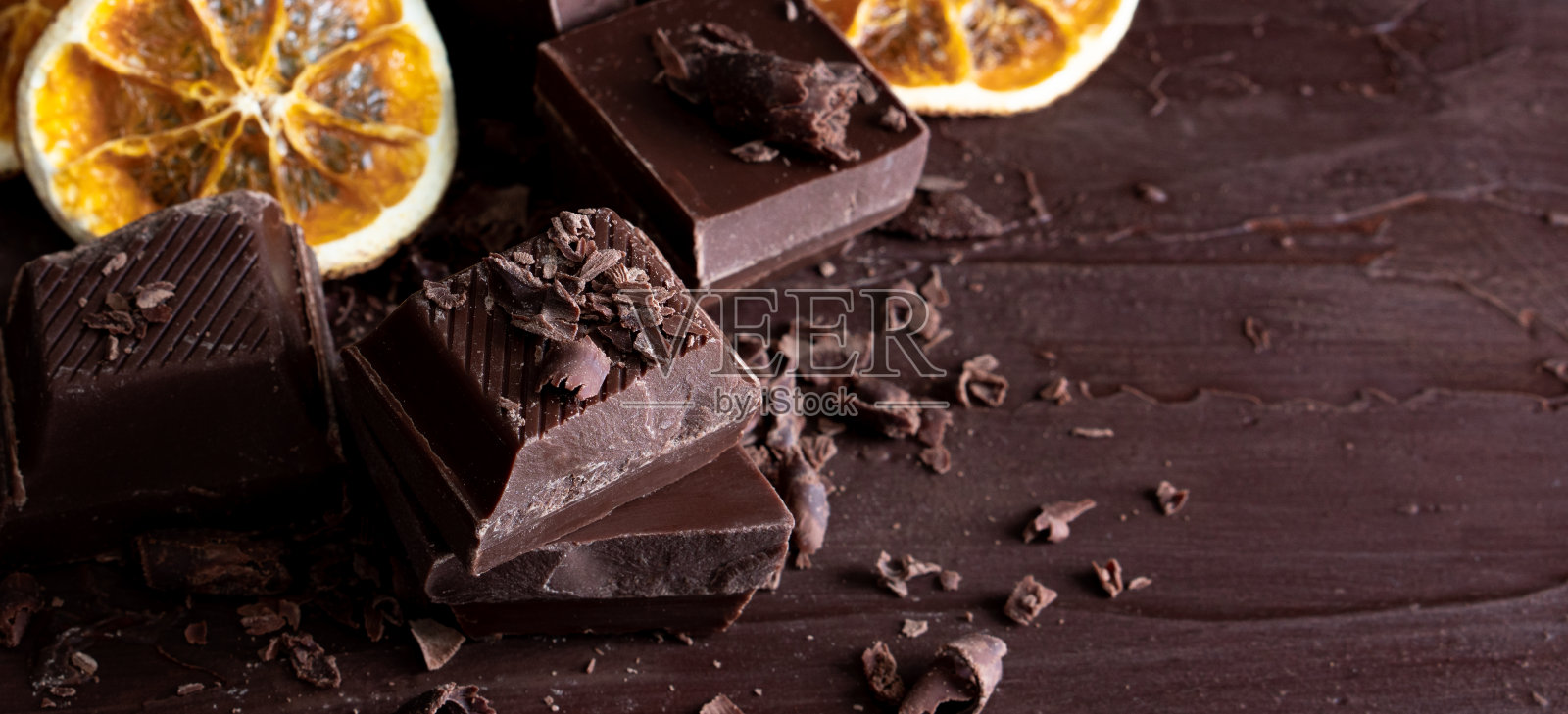 有机食品零食，美味的甜甜点，牛奶，黑巧克力棒，大近景，破碎的幻灯片片，水果，橘子，树莓，榛子，坚果，可可粉，木桌子作为新年圣诞礼物照片摄影图片