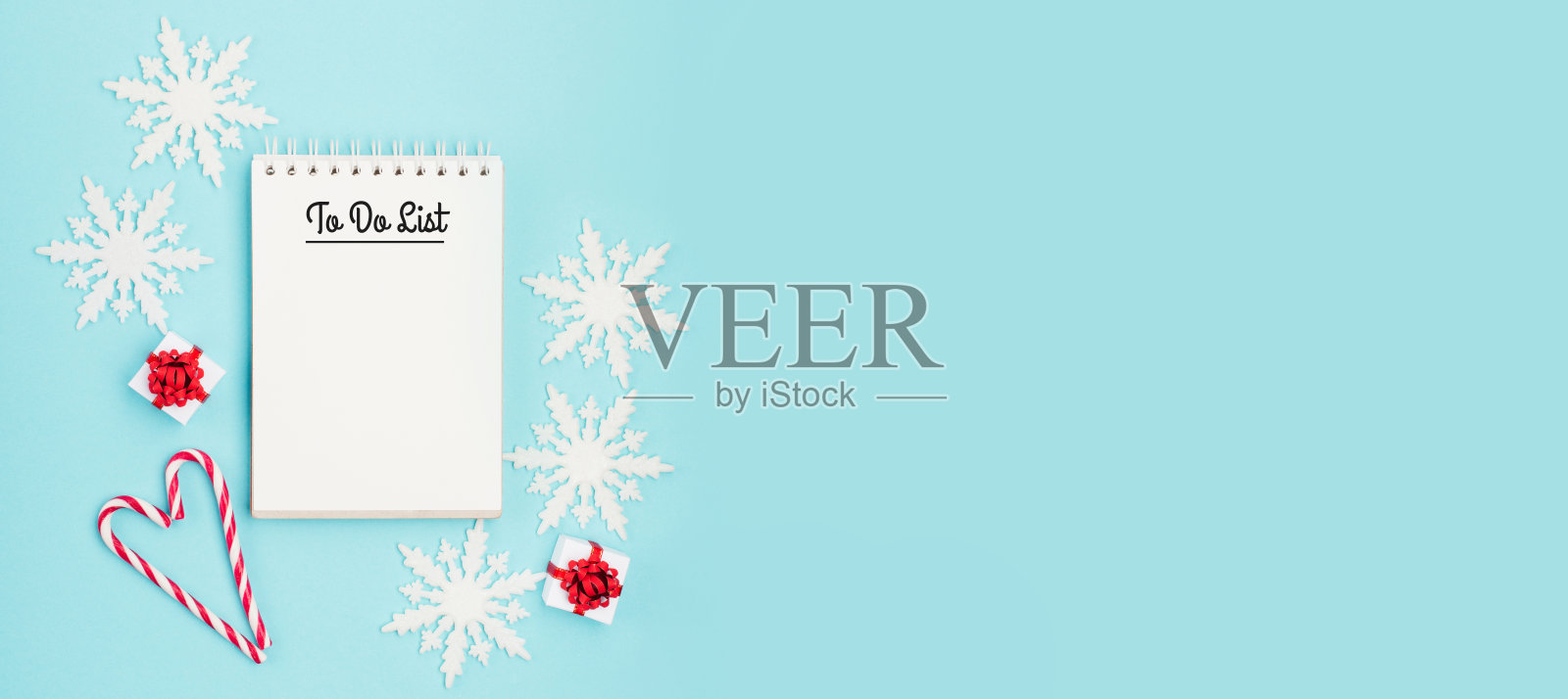 空的白色笔记本，礼物，雪花，心形糖果拐杖在柔和的蓝色背景。照片摄影图片