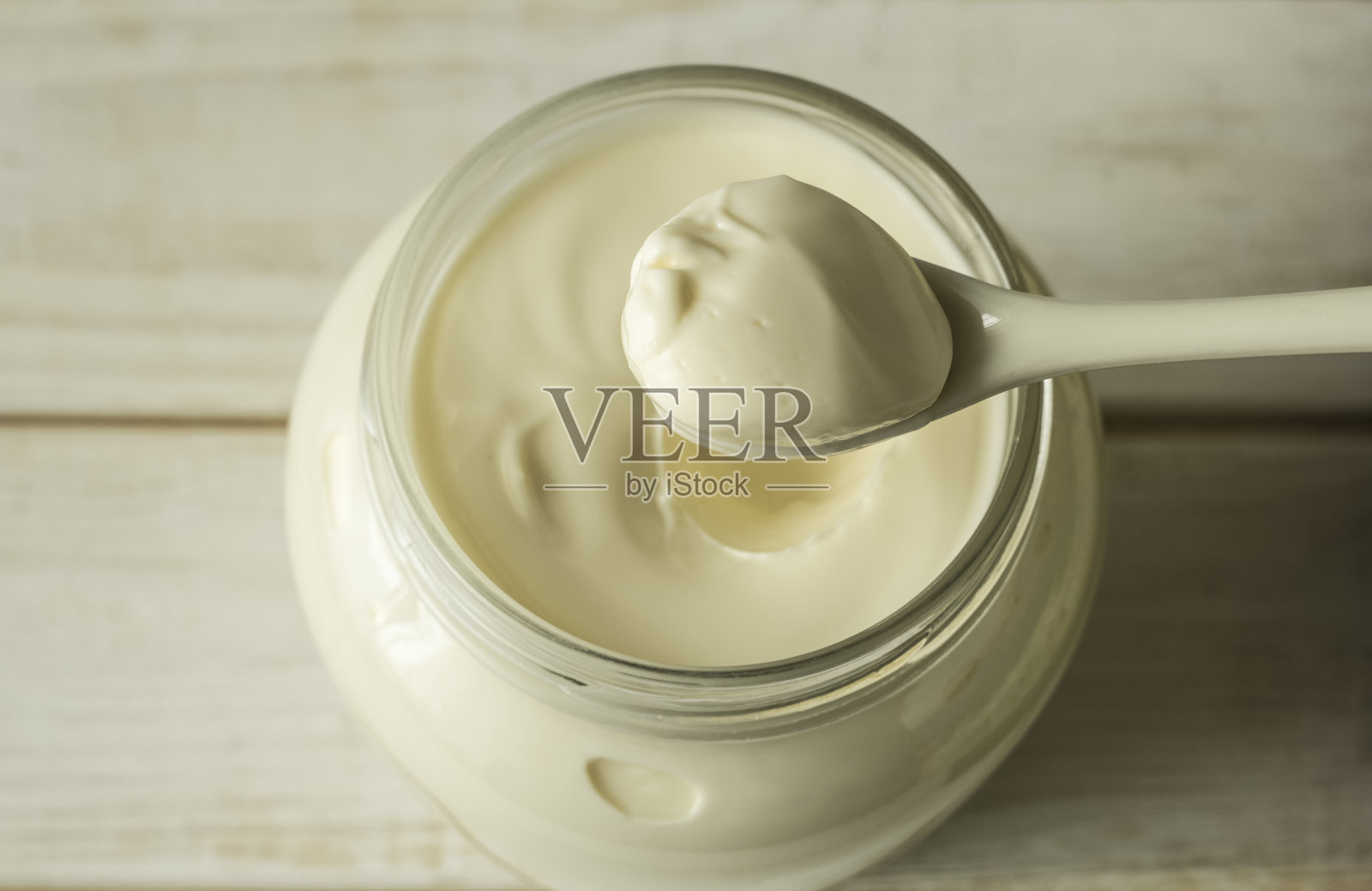 蛋黄酱装在玻璃罐里，勺子放在白色的木板上。照片摄影图片