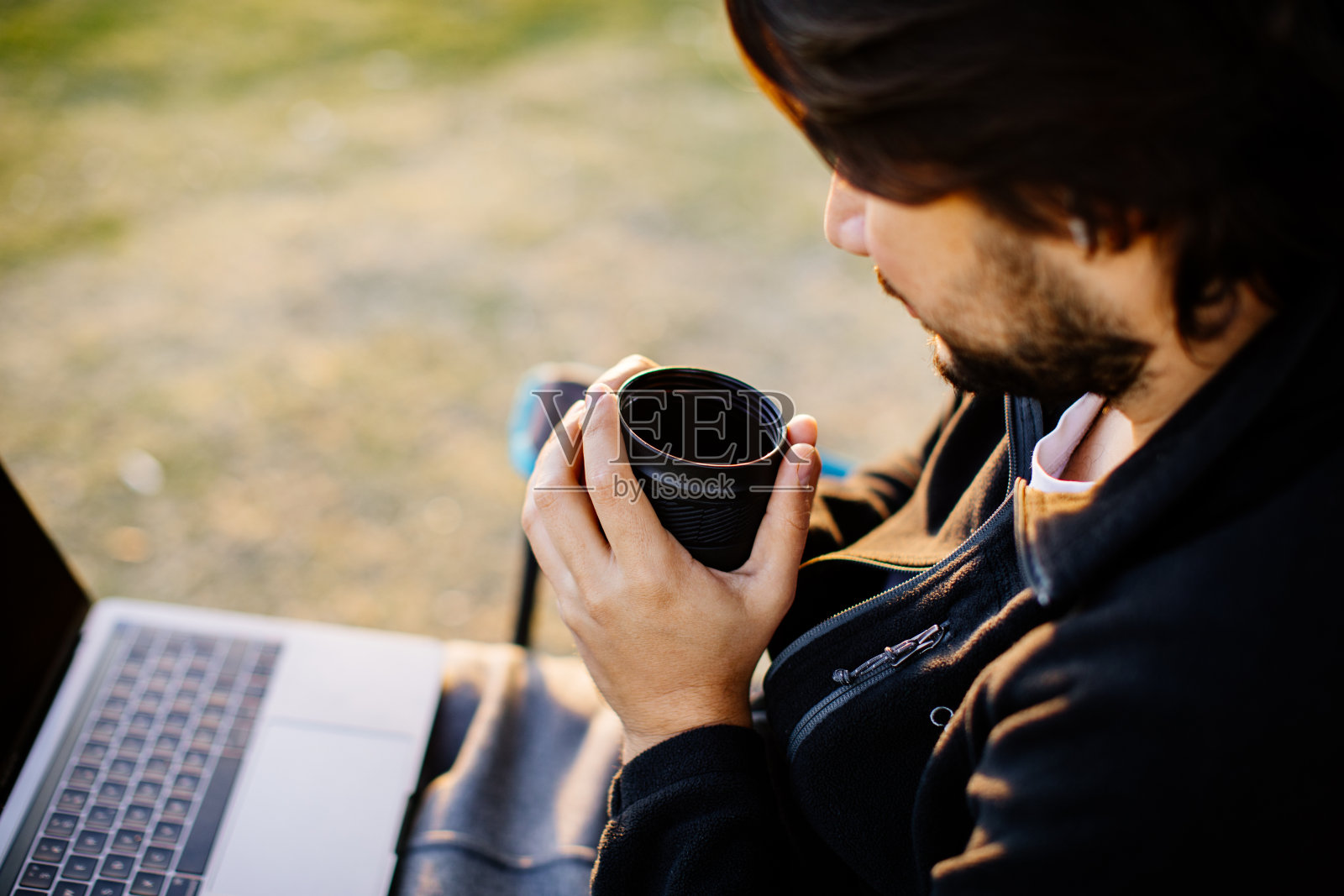 年轻的自由职业者坐在公园里，拿着笔记本电脑，喝着咖啡。在任何地方工作照片摄影图片