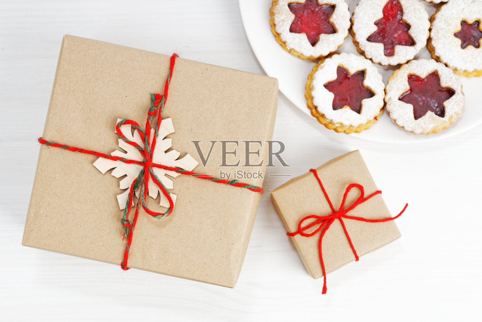 牛皮纸包装的礼品盒和自制的饼干放在白色的木桌上。前视图。照片摄影图片