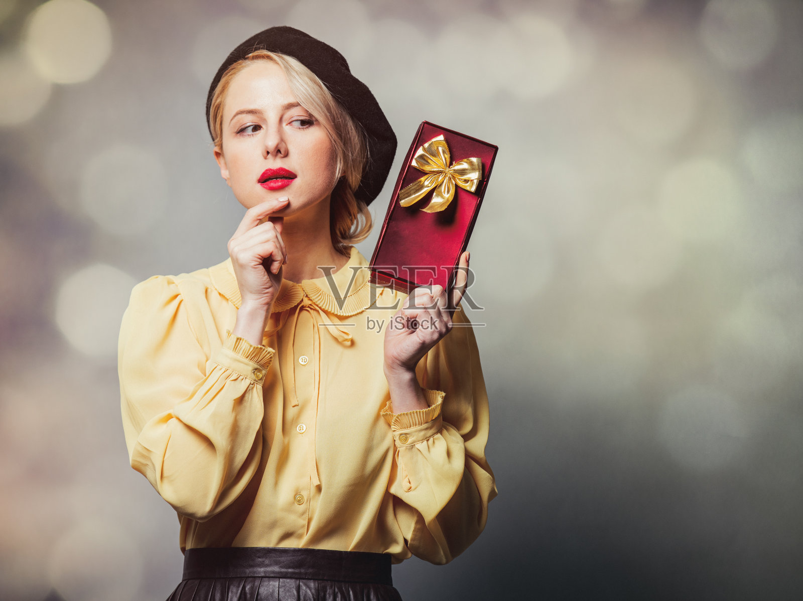 漂亮的女孩穿着复古的衣服，在灰色的背景上带着礼物照片摄影图片