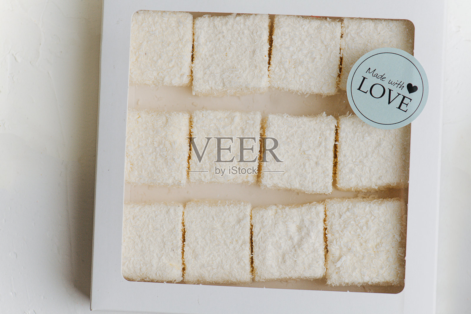 白色的土耳其软糖在椰子刨花下，在一个有窗的盒子。前视图。照片摄影图片