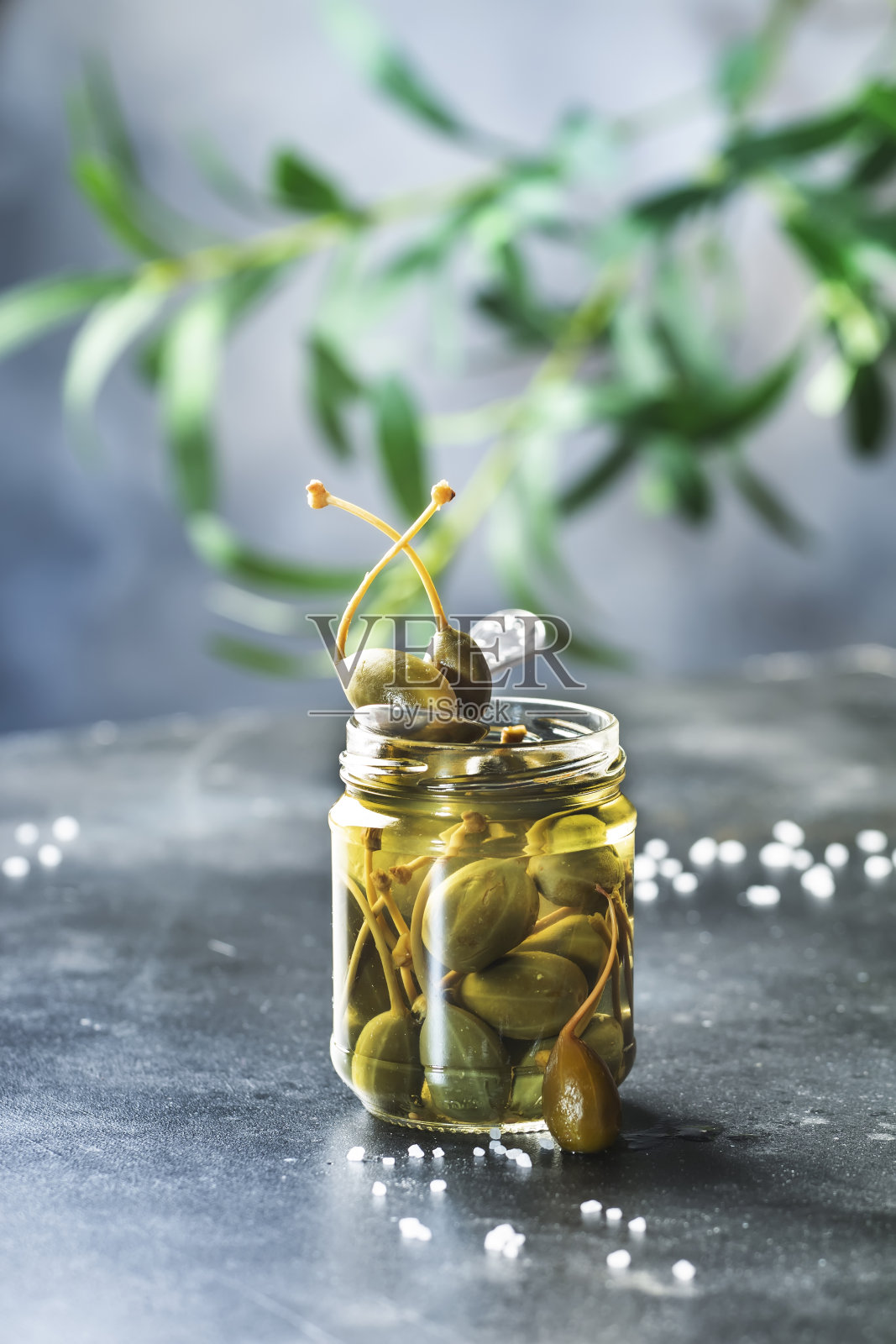 腌制或腌制的酸豆罐头放在灰色的厨房桌子上照片摄影图片