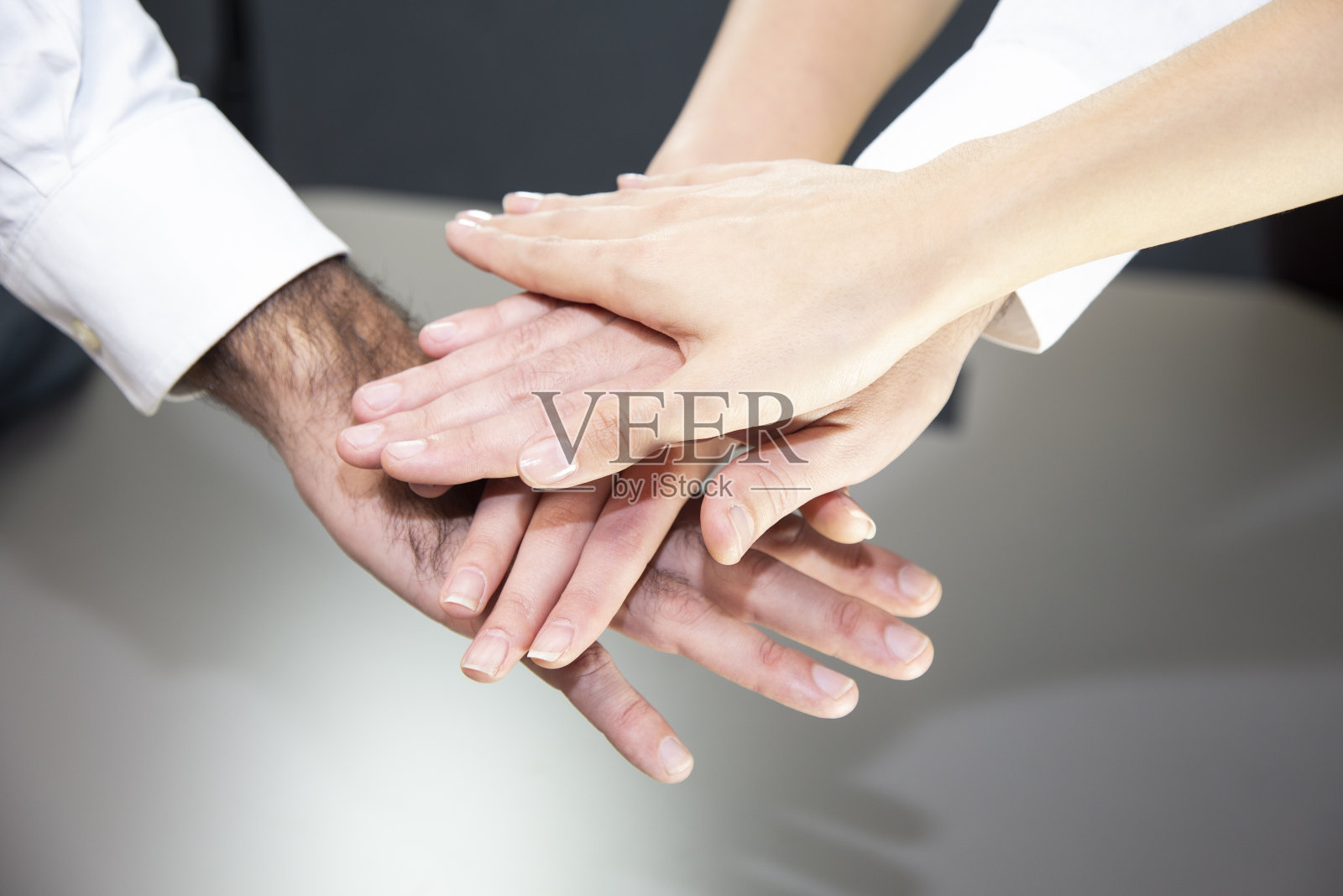 近距离俯瞰年轻的商人们把他们的手放在一起。堆栈的手中。团结协作的理念。照片摄影图片