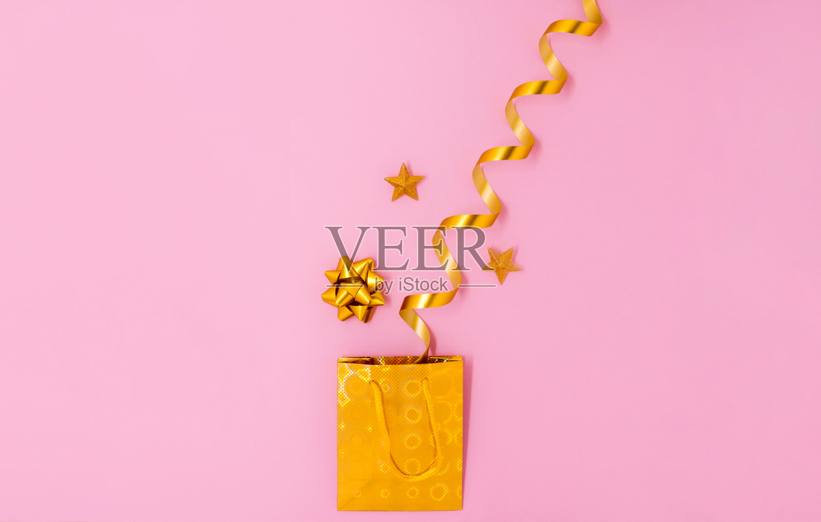 节日的金色礼品袋与丝带和星星在粉红色的背景。平躺，俯视图照片摄影图片
