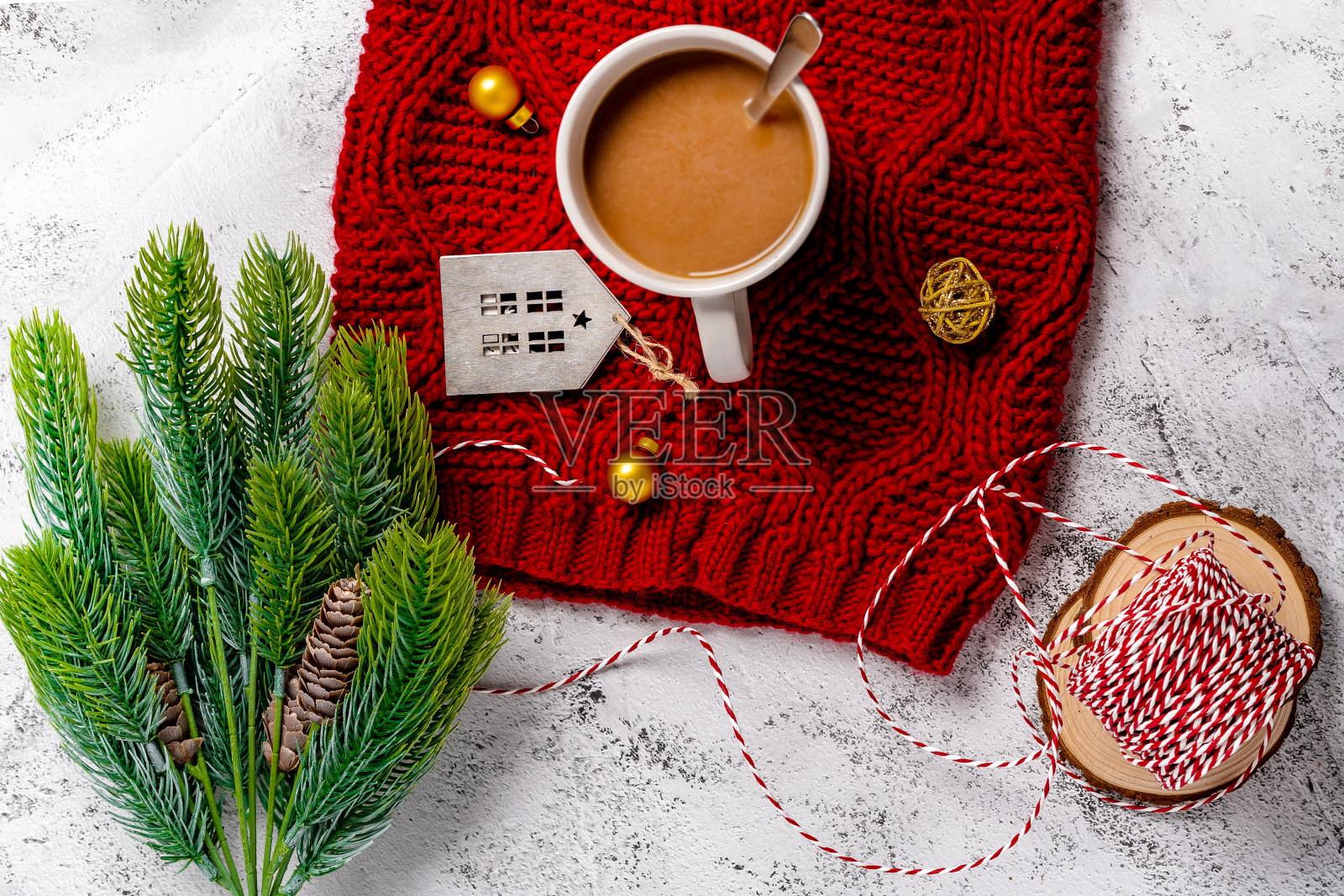 木制桌子上，热的节日咖啡饮料被圣诞物品包围着。红色围巾上的智能手机。舒适的假期和新年的概念。照片摄影图片