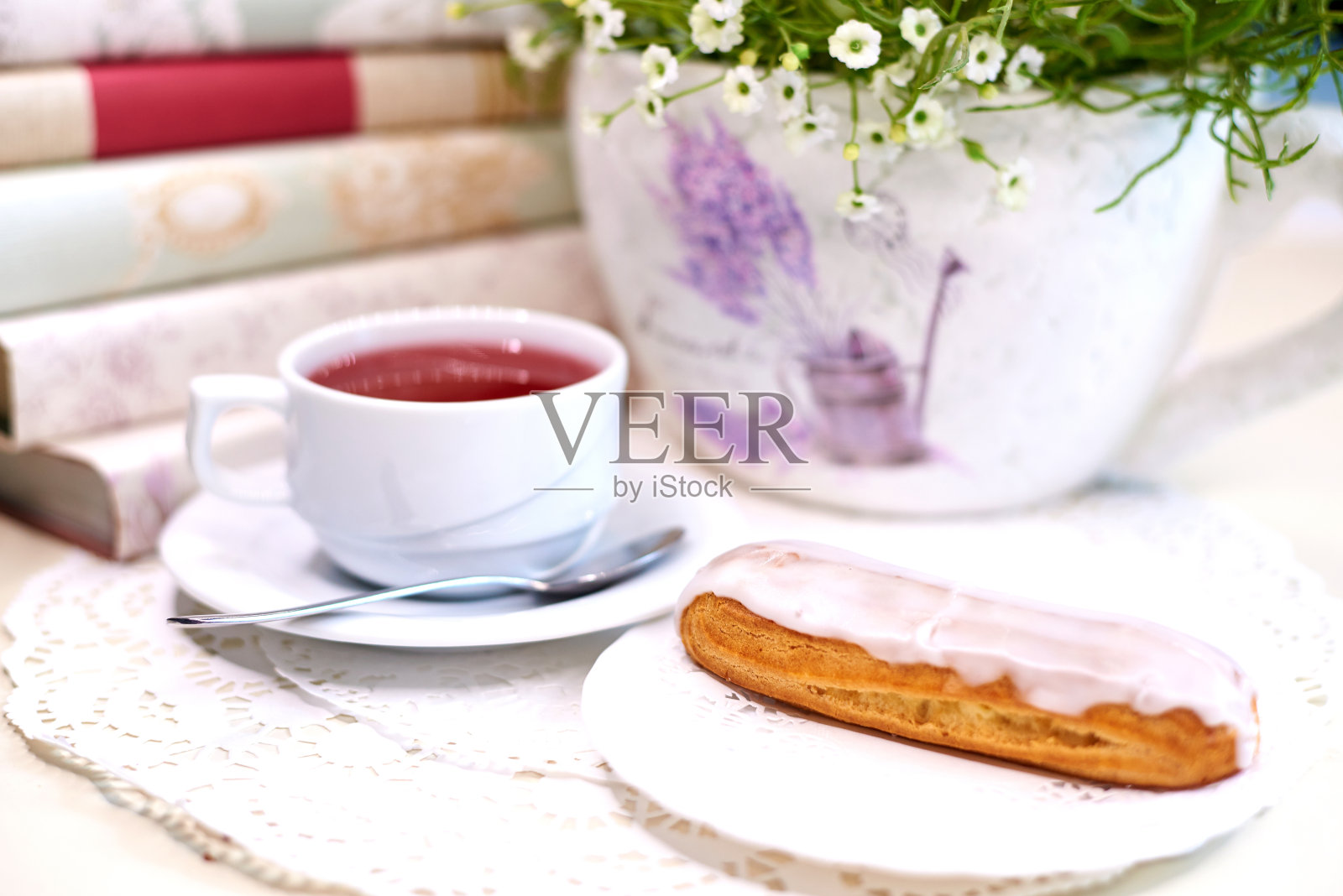 桌上有茶和蛋糕，还有鲜花和书。照片摄影图片