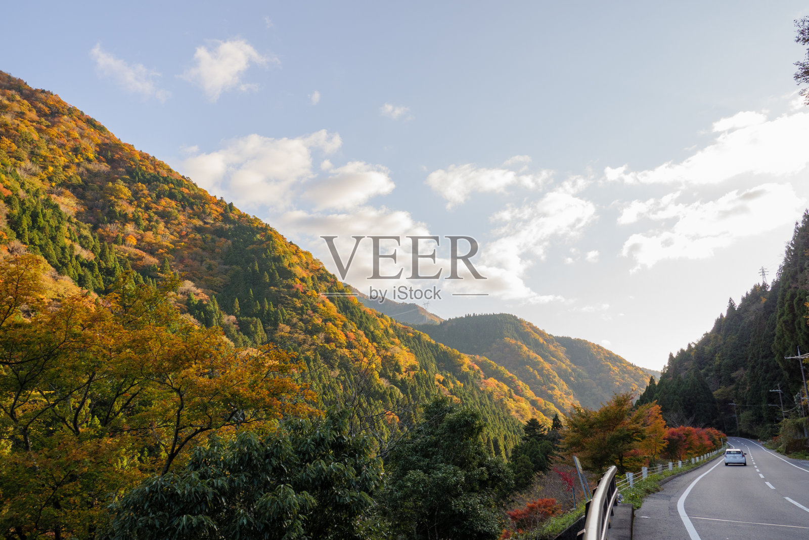 面对着被夕阳照亮的秋山的道路照片摄影图片