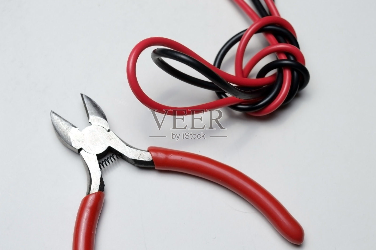 白色背景上纠结的双音电线和断线钳。照片摄影图片