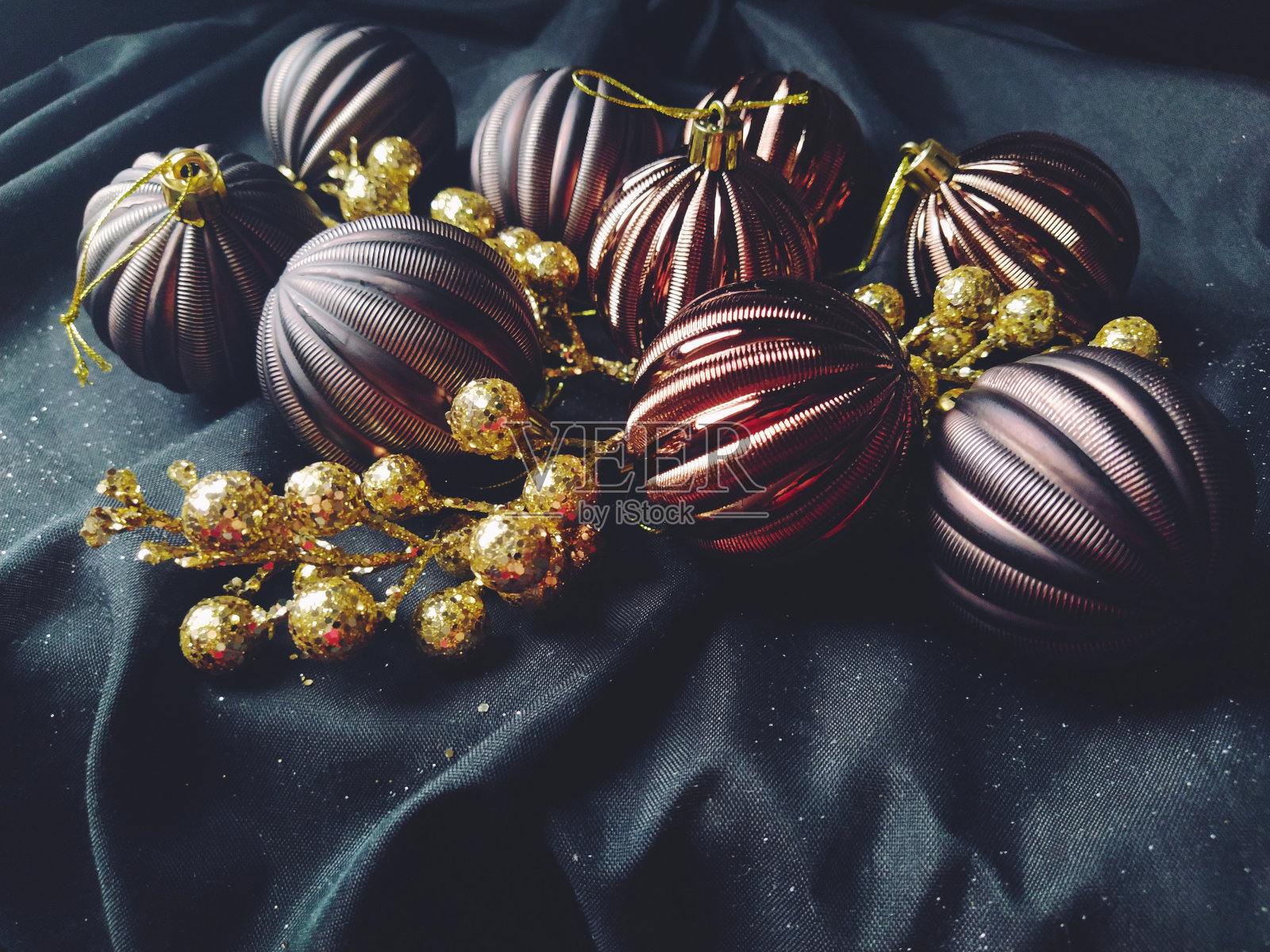 贺卡的新年和圣诞节装饰，圣诞装饰和闪闪发光的黑色背景。褐色亮晶晶的条纹球，花和白色的雪花，金色的小树枝和浆果照片摄影图片