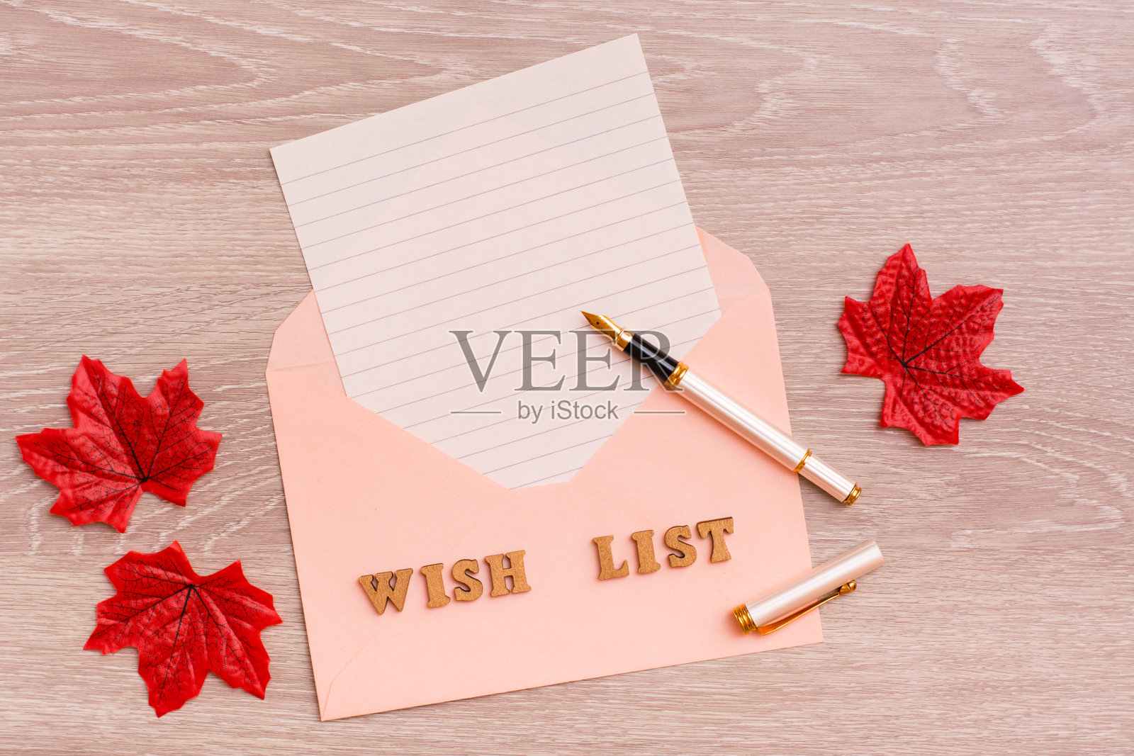 愿望清单。空白的信封纸，钢笔和枫树叶木制背景。前视图。照片摄影图片