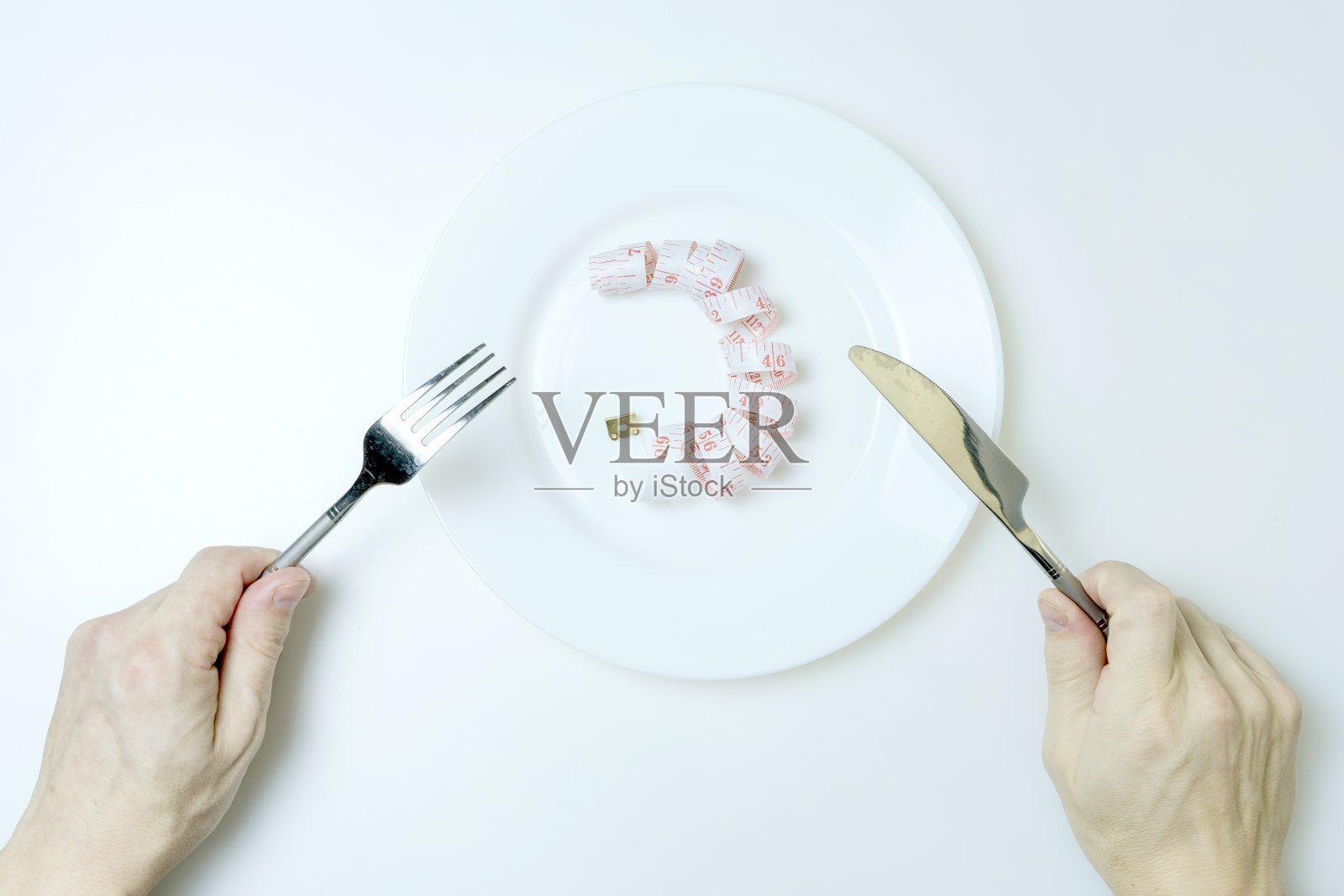 男人的手拿着刀和叉。在白色背景上的板上测量卷尺。饮食的概念。照片摄影图片